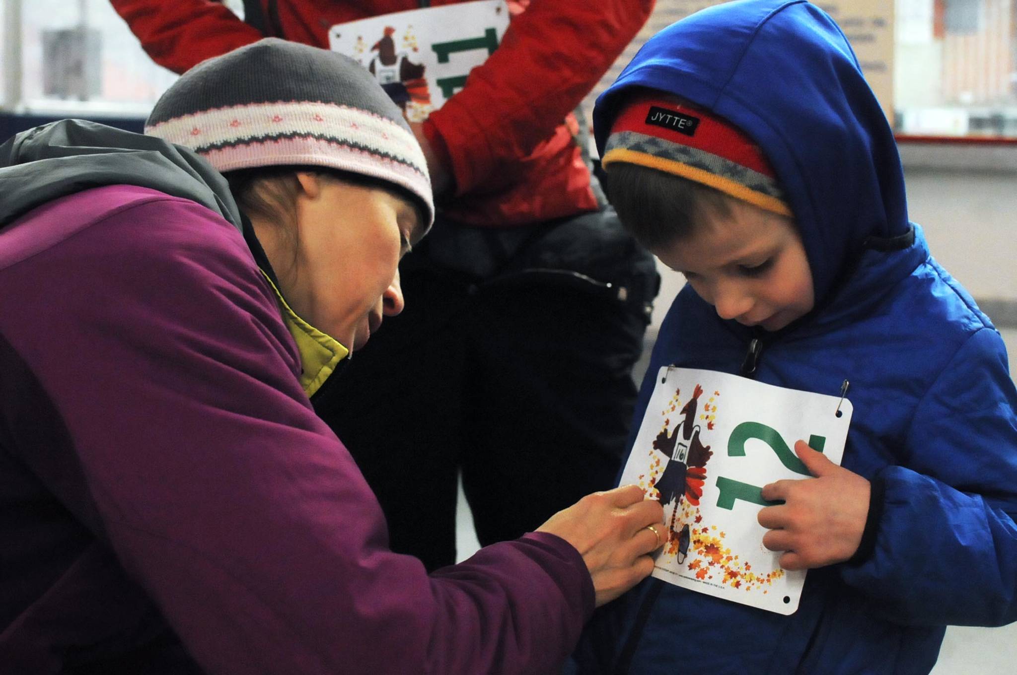 Carly Reimer pins a bib on her son Gus Reimer, 4, for the 1-mile run at the Turkey Trot run held at the Soldotna Regional Sports Complex on Thursday, Nov. 23, 2017 in Soldotna, Alaska. (Photo by Elizabeth Earl/Peninsula Clarion)