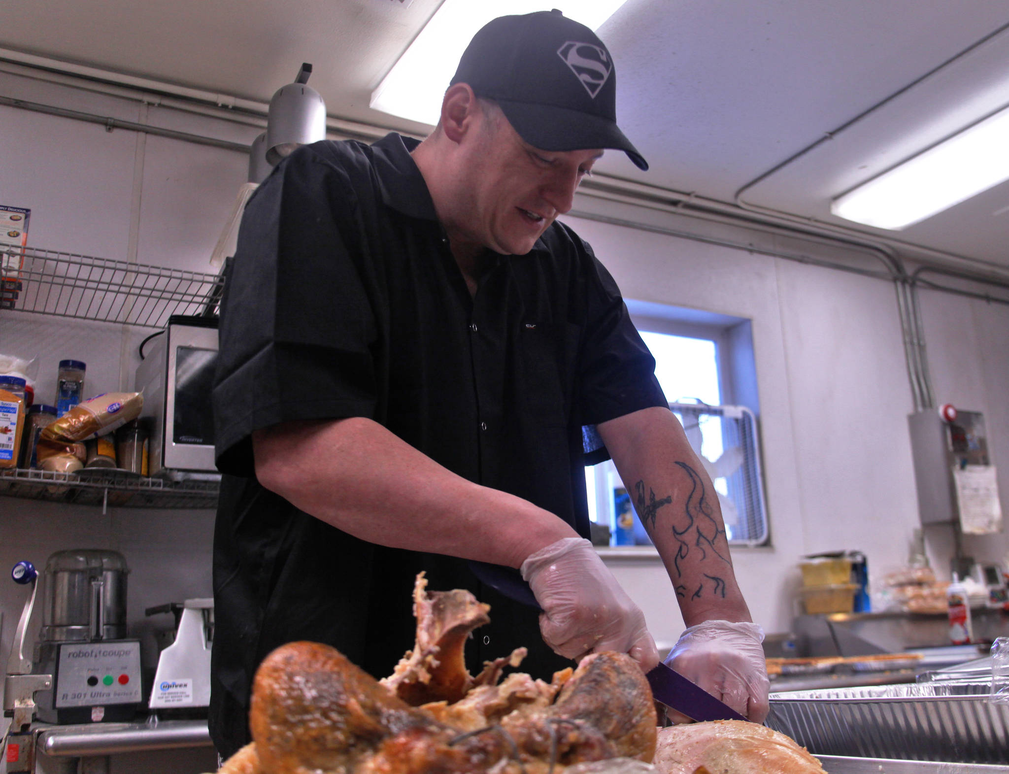 Kitchen manager Beau Jamison of the Duck Inn slices the breast meat of one of the twelve turkeys he prepared for the restuarant’s Thanksgiving dinner at the Duck Inn on Kalifornsky Beach Road on Thursday, Nov. 23, 2017 near Soldotna, Alaska. This Thanksgiving — the twelfth for which that Jamison has prepared the Duck Inn’s traditional meal, closes a year of hardship for Jamison — in August he recieved a clean diagnosis after struggling with lymphoma since October 2016, and it’s his first year as a single father after his wife’s death. (Ben Boettger/Peninsula Clarion)