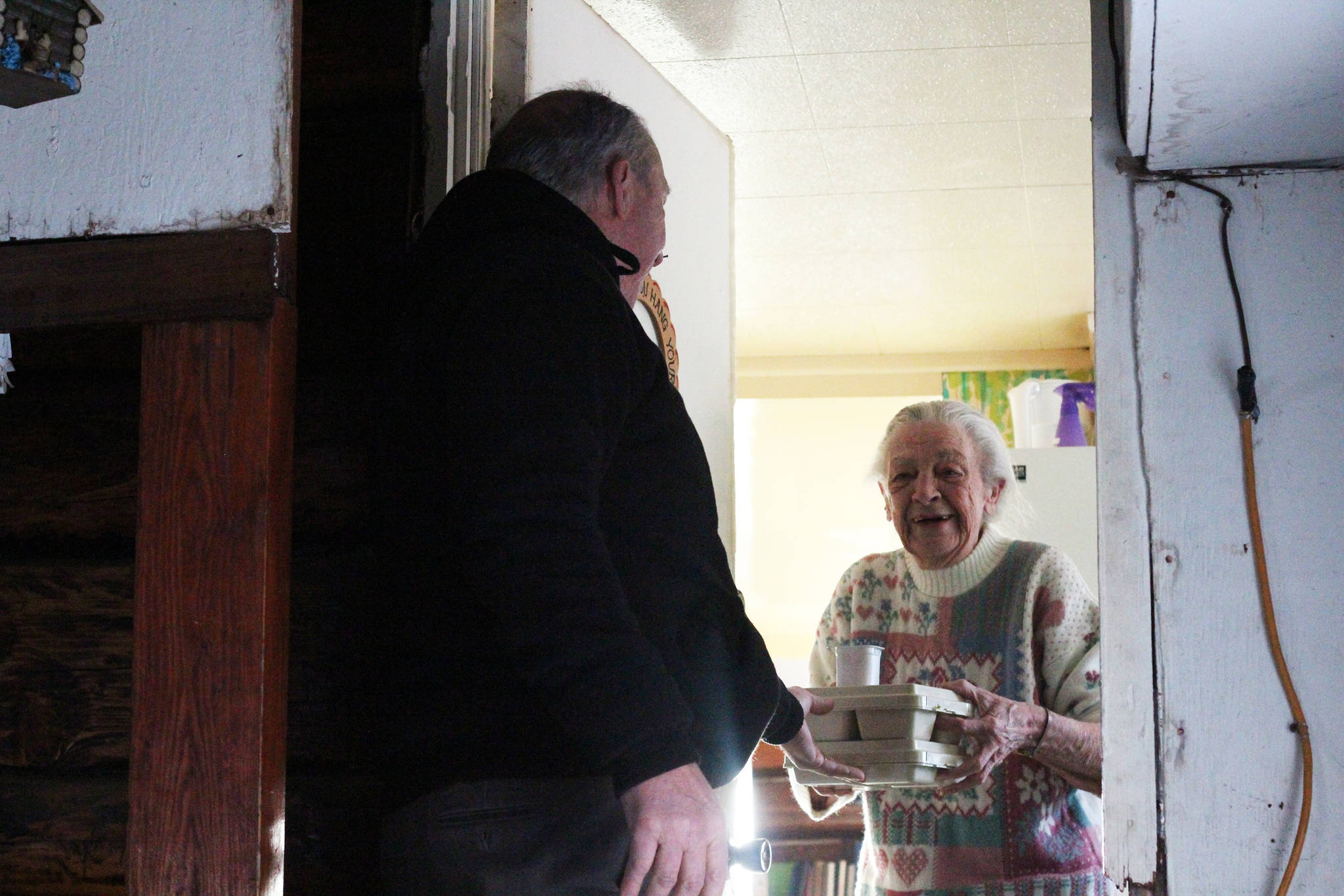 Mayor Bryan Zak delivers the first meal to be driven by the Homer Senior Citizen Center’s new Subaru to resident Marilyn Prevost on Monday, Nov. 20, 2017 in Homer, Alaska. Prevost, 80, has lived in Homer for 73 years and receives some of the more than 3,000 meals given out by the program each year. (Photo by Megan Pacer/Homer News)