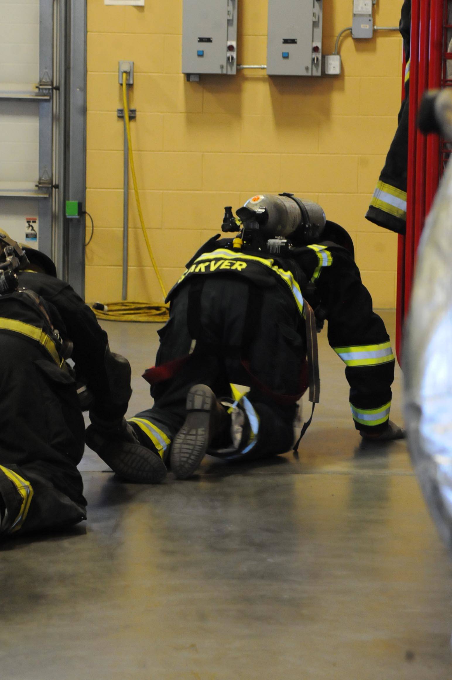 Kenai River Brown Bears player David Kaplan (right) leads a line of three players on a “right hand search” drill during a tour and training demonstration at the Kenai Emergency Operations Center on the Kenai Municipal Airport on Tuesday, Nov. 28, 2017 in Kenai, Alaska. Kenai Fire Department firefighters walked the Brown Bears players through some of the training and tools firefighters use to give them an idea of what a career in fire response is like. (Photo by Elizabeth Earl/Peninsula Clarion)