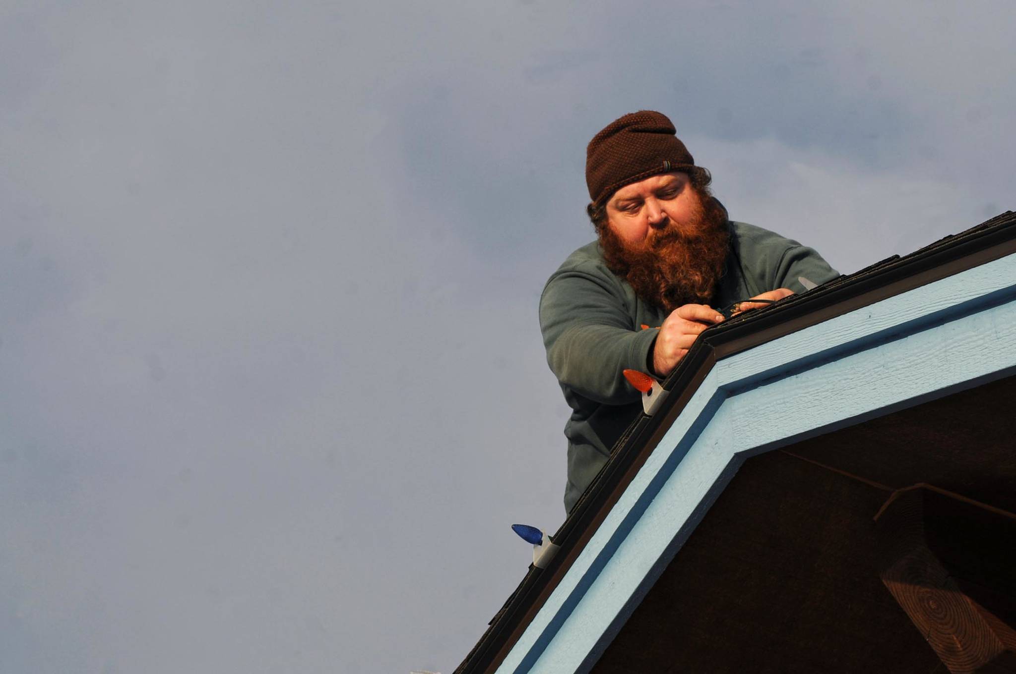 Jason Rainwater of Dutch Boy Landscaping mounts a string of Christmas lights to the edge of the Salamatof Native Association building’s roof on Wednesday, Nov. 29, 2017 in Kenai, Alaska. All around the central Kenai Peninsula, homes and businesses are lighting up after the Thanksgiving holiday in time for Christmas. Rainwater said the workers install the lights on a timer to come on in the morning and evening and turn off during the day. (Photo by Elizabeth Earl/Peninsula Clarion) 