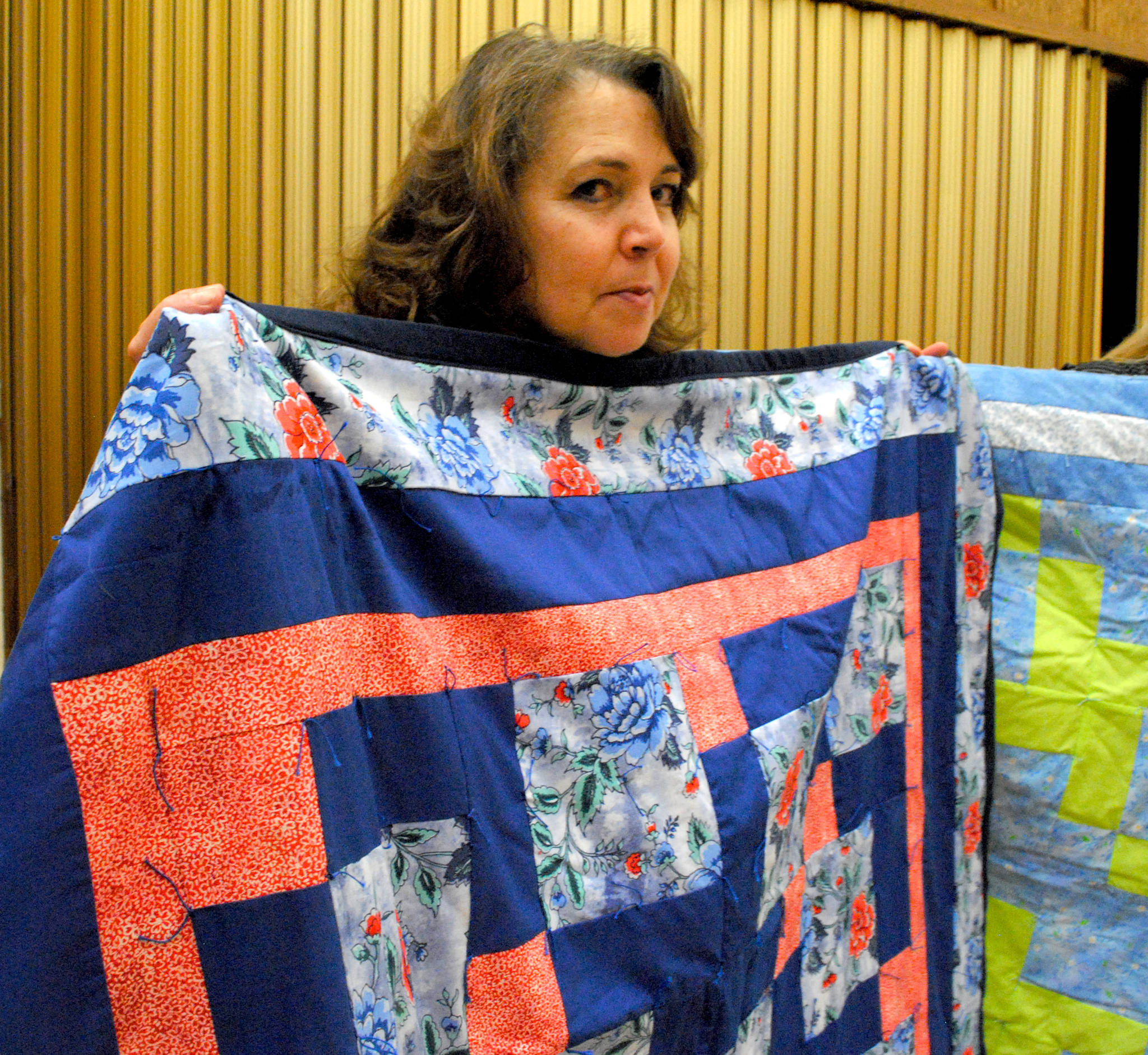 Christine Carlson of Kasilof shows off one of her quilted creations during the Church of Jesus Christ of Latter-Day Saints monthly humanitarian potluck meeting at the LDS Church in Soldotna, Alaska on Nov. 30, 2017. Carlson has been quilting since an early age and has made 35 quilts this year for different charities and organizations. (Photo by Kat Sorensen/Peninsula Clarion)