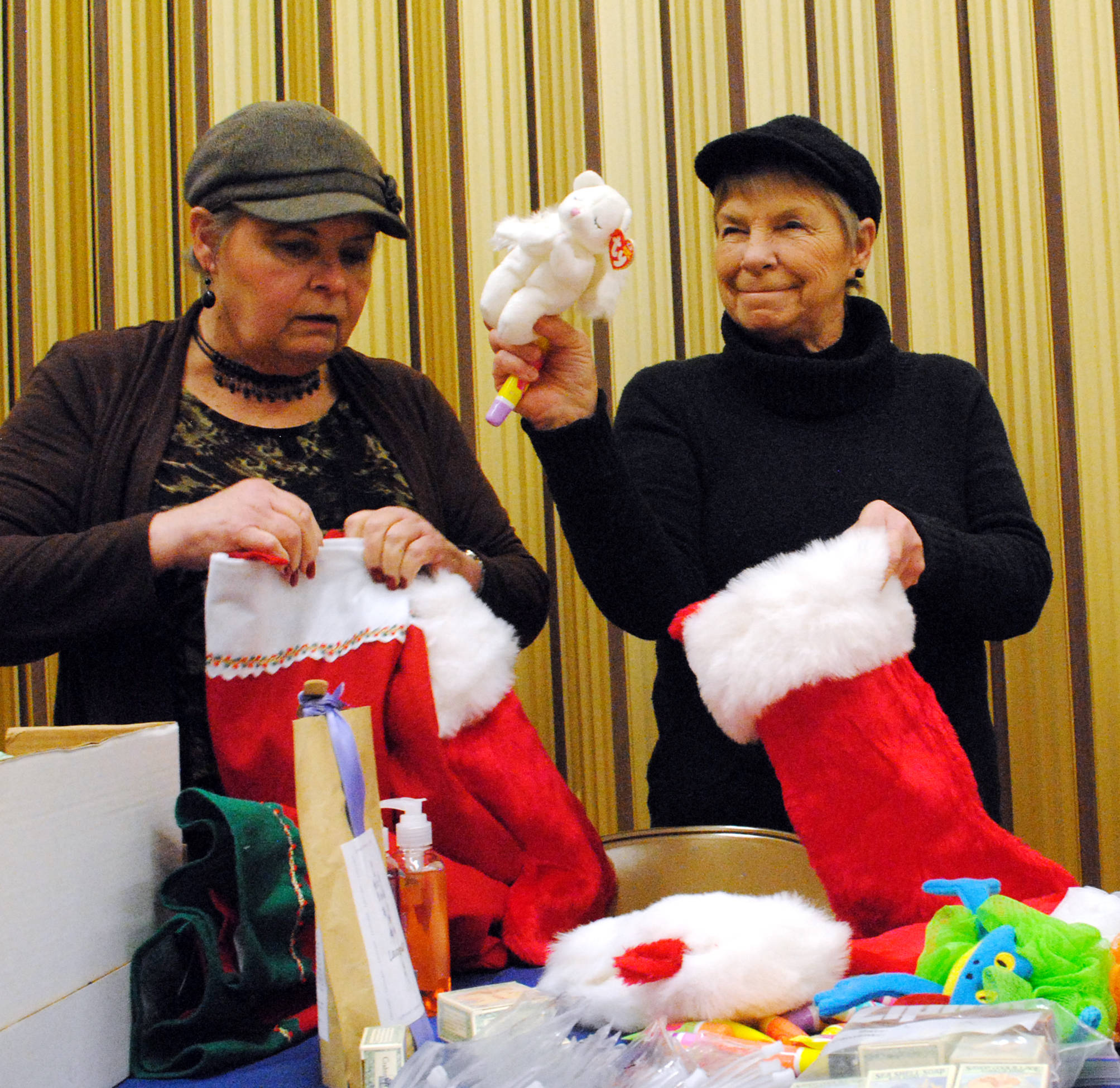 Jerri Scott, left, and Bobbi Steejes stuff stockings with holiday gifts on Thursday, Nov. 30 at the LDS Church in Soldotna, AK. The stockings will be donated to Love In the Name of Christ of the Kenai Peninsula, an inter-denominational Christian organization, which is hosting a Christmas event for families in need on Dec. 23. (Photo by Kat Sorensen/Peninsula Clarion)