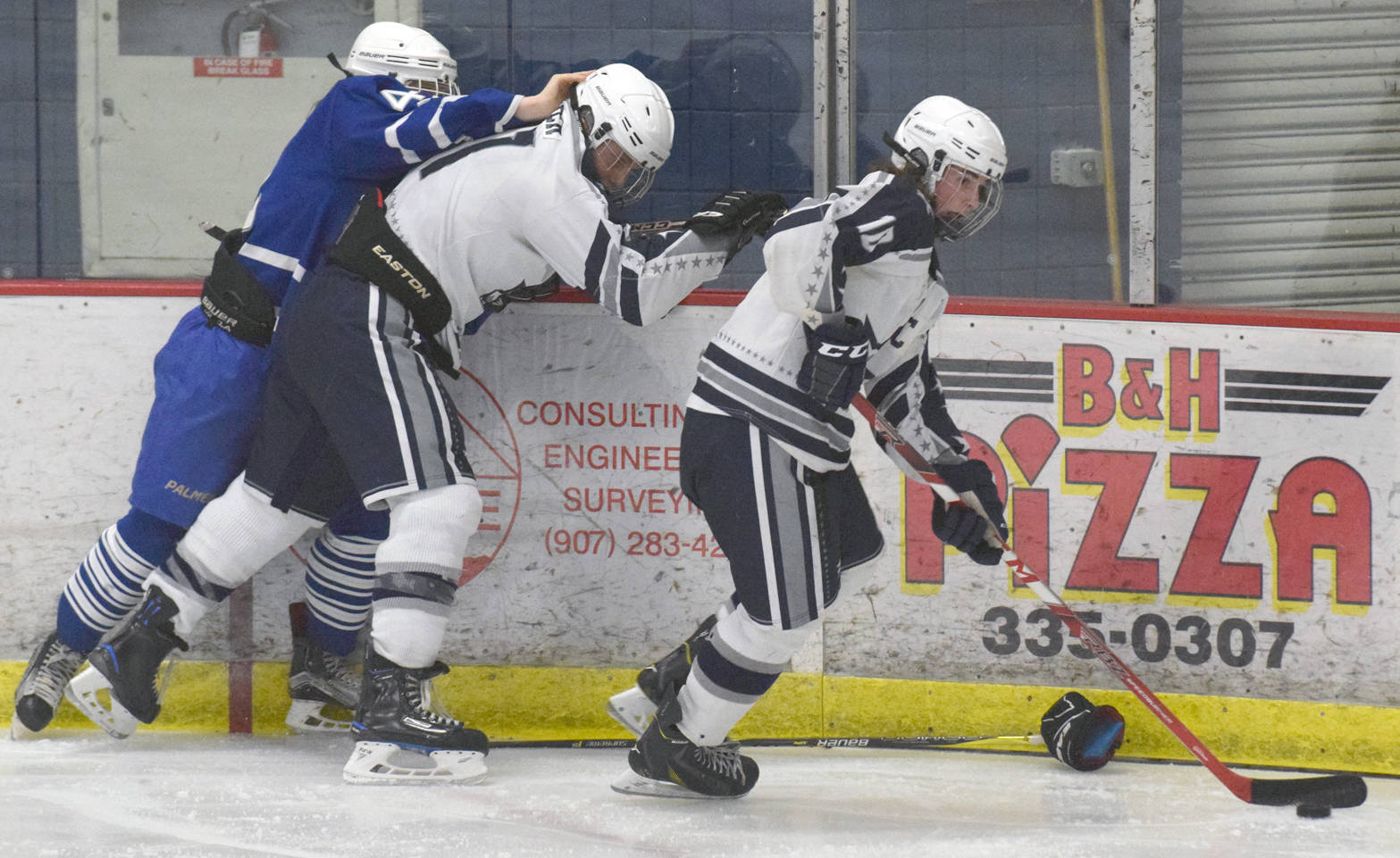 Soldotna’s Braxton Urban skates off with the puck while Palmer’s Nathan Hooks and Soldotna’s Levi Brenner battle along the boards Thursday, Nov. 30, 2017, at the Soldotna Regional Sports Complex. (Photo by Jeff Helminiak/Peninsula Clarion)