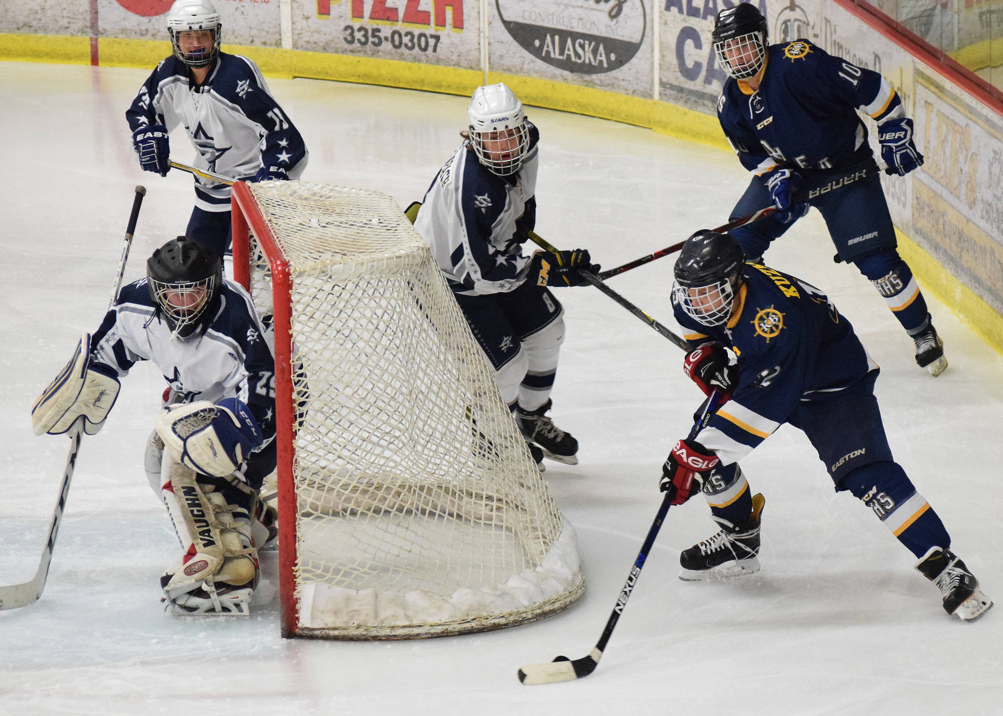 Homer skater Dimitry Kuzmin (right) pulls the puck around Soldotna goaltender Kenzie Powell Tuesday night at the Soldotna Regional Sports Complex. (Photo by Joey Klecka/Peninsula Clarion)