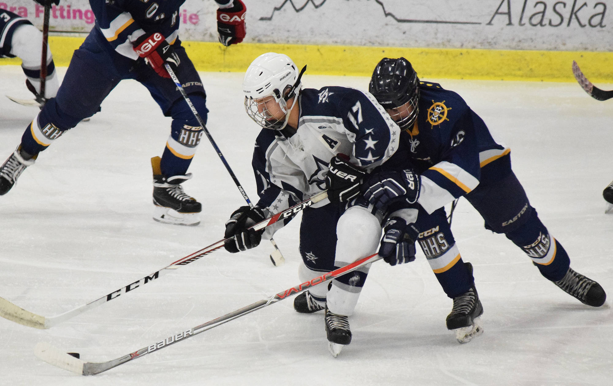 Soldotna skater Wyatt Medcoff (left) battles for the puck against Homer’s Ethan Pitzman Tuesday night at the Soldotna Regional Sports Complex. (Photo by Joey Klecka/Peninsula Clarion)