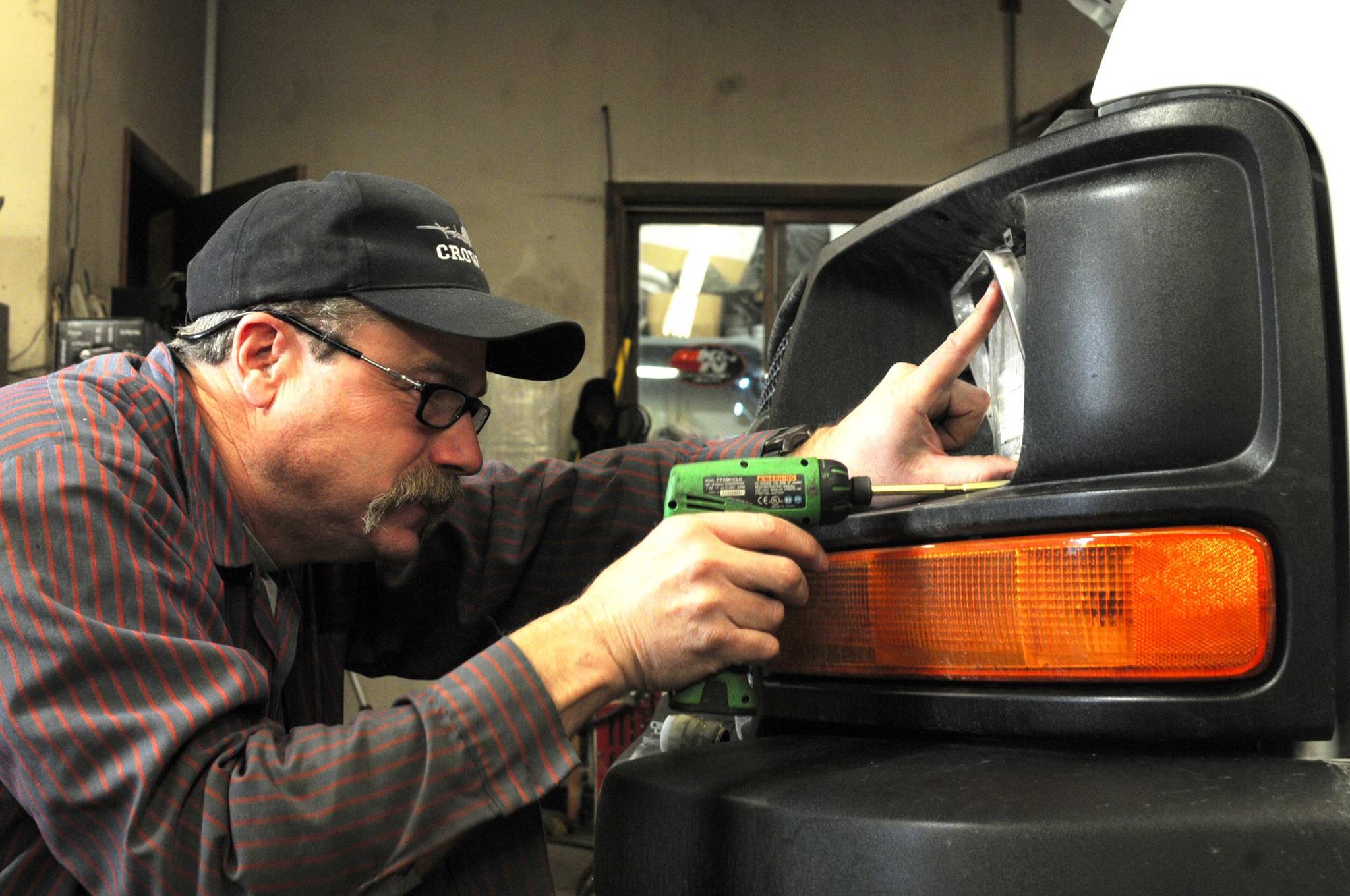Gary Dawkins, owner of Gary’s Auto Electric, removes an old headlight from a customer’s van Monday, Dec. 11, 2017 at his shop near Soldotna, Alaska. After more than 30 years in the business, Dawkins will close Gary’s Auto Electric on Friday with one additional clearout opening scheduled for Jan. 15. (Photo by Elizabeth Earl/Peninsula Clarion)