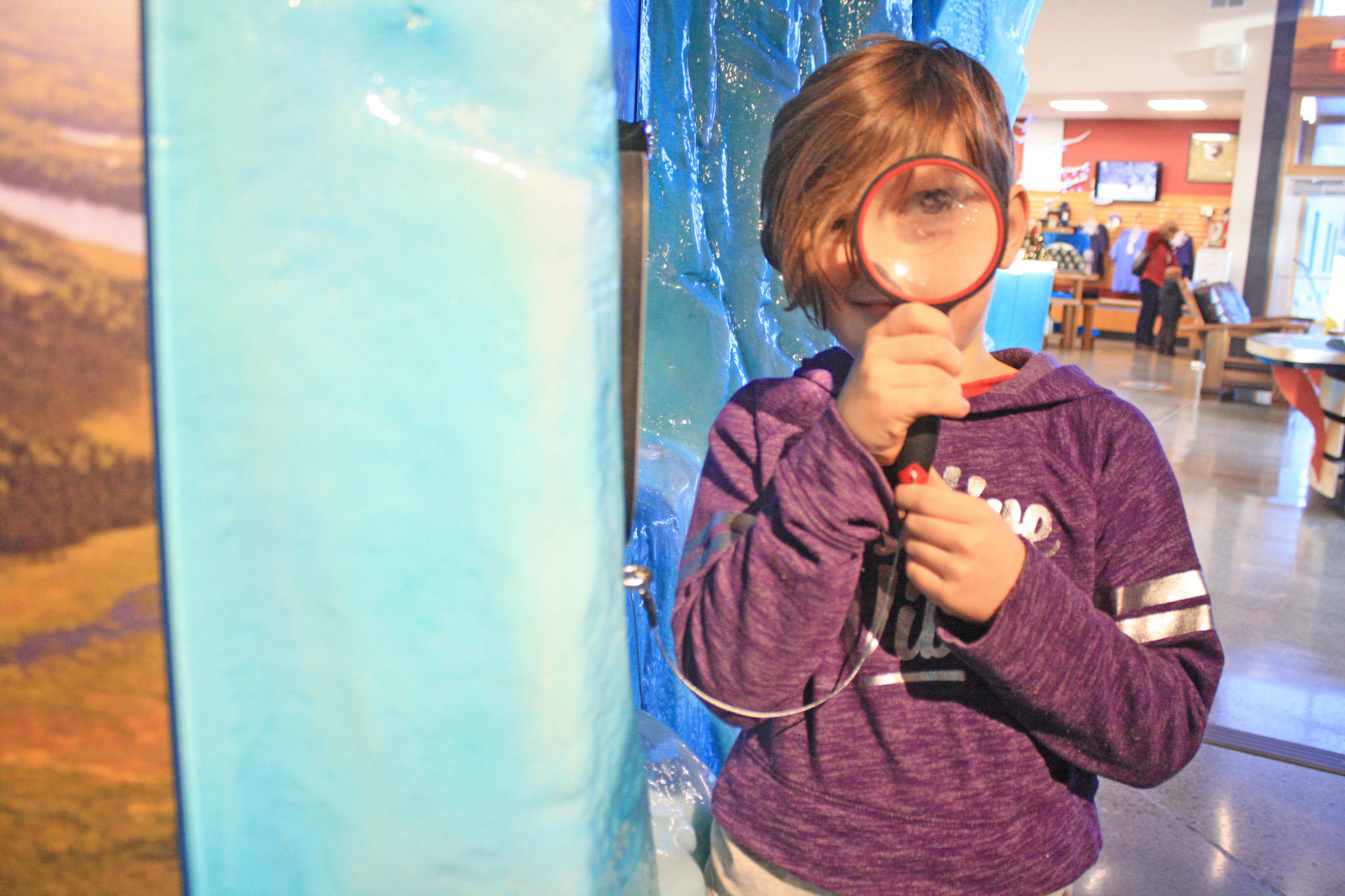 Alexandra Stoaks, 8, peers through a magnifying glass featured in one of the exhibits at the Kenai National Wildlife Refuge Visitor Center. Stoaks and her family attended the Dec. 27 Winter Break Family Fun Day at the center. The visitor center hosts community events throughout the year, including weekly winter walks and film screenings. (Photo by Erin Thompson/Peninsula Clarion)