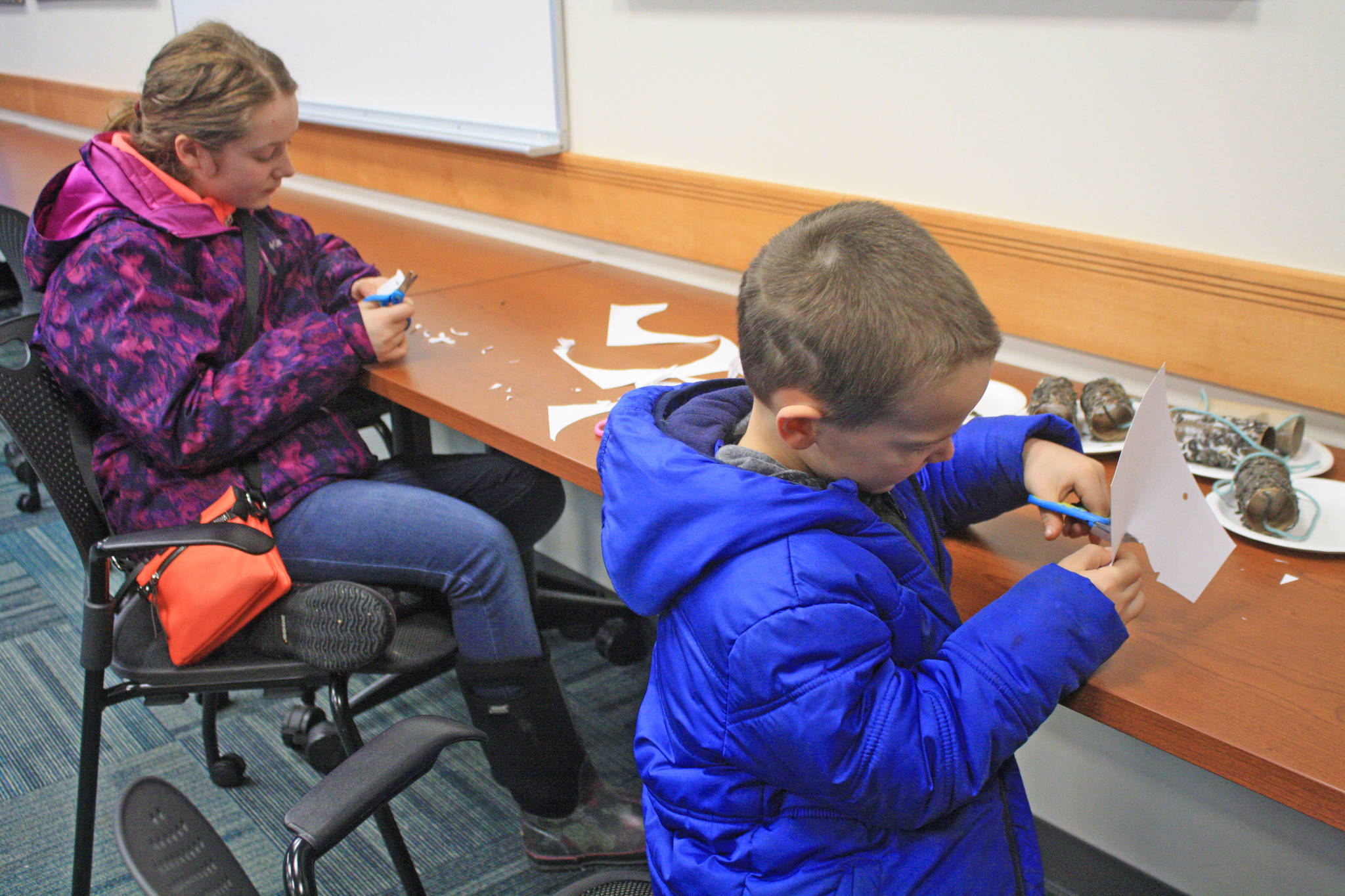 Audrey Larson, 13, and Phillip Larson, 6, create paper snowflakes at the Kenai National Wildlife Refuge Visitor Center Winter Break Family Fun Day on Dec. 27. The event is just one of the many activities hosted year-round by the center. (Photo by Erin Thompson/Peninsula Clarion)