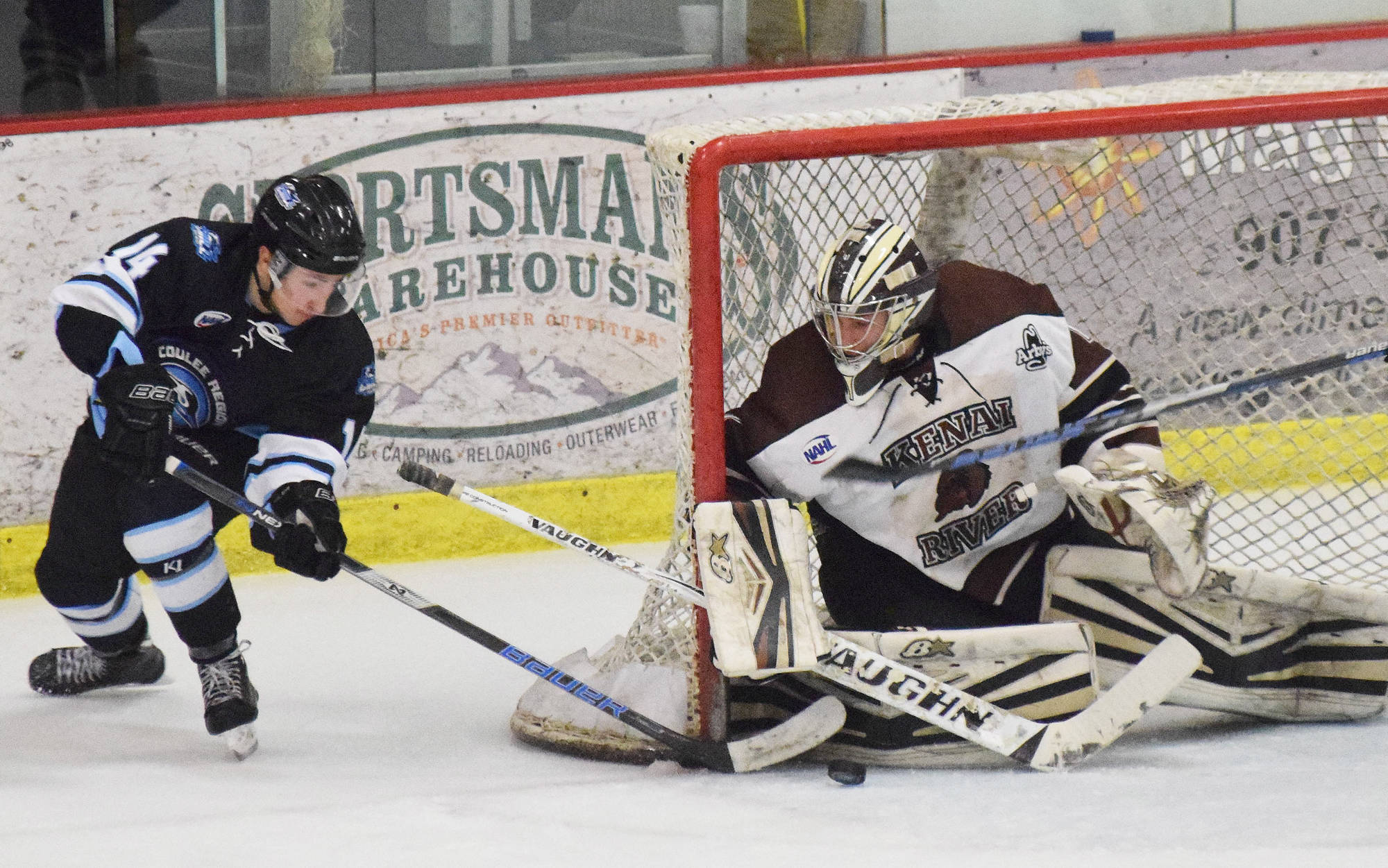 Coulee Region forward Connor Szmul (left) attempts to slip the puck by Kenai River goaltender Gavin Enright Friday night at the Soldotna Regional Sports Complex. (Photo by Joey Klecka/Peninsula Clarion)