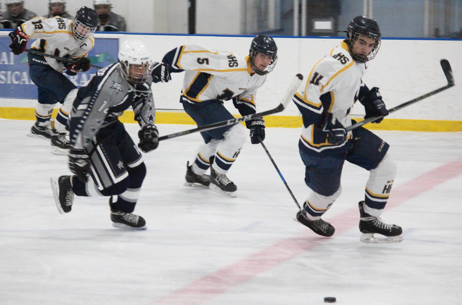 Homer hockey players Dimitry Kuzmin (12), Douglas Dean (5) and Charlie Menke (11) chase after the puck along with Soldotna’s Alex Montague during their game Tuesday, Jan. 16, 2017, at Kevin Bell Arena in Homer. The Mariners beat the Stars 10-1. (Photo by Megan Pacer/Homer News)