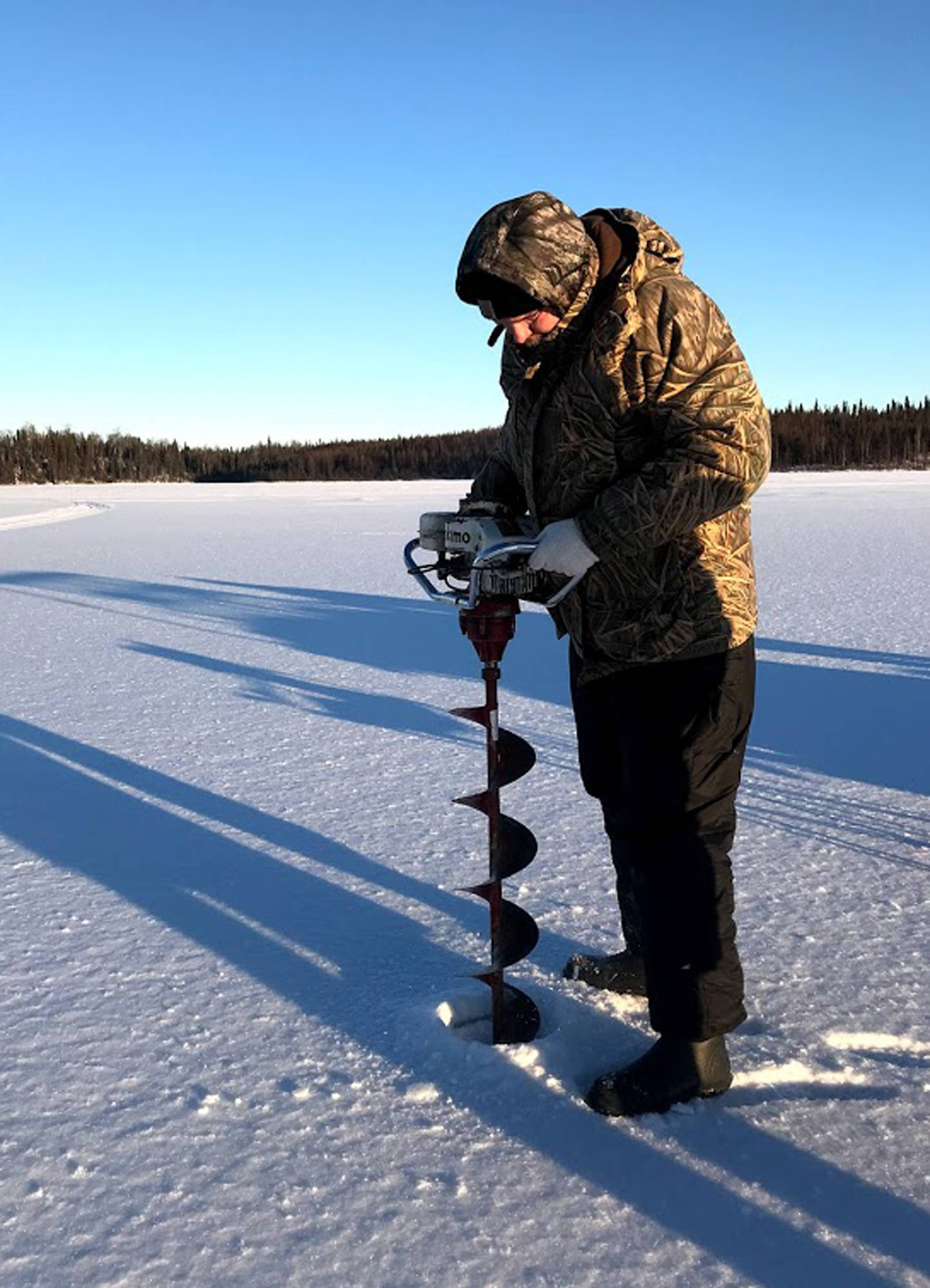 LEFT: Jon Watson, pastor at Peninsula Christian Center of Soldotna and avid ice fisherman, drills a series of holes in the ice on Sprit Lake. The ice was about eight inches deep.