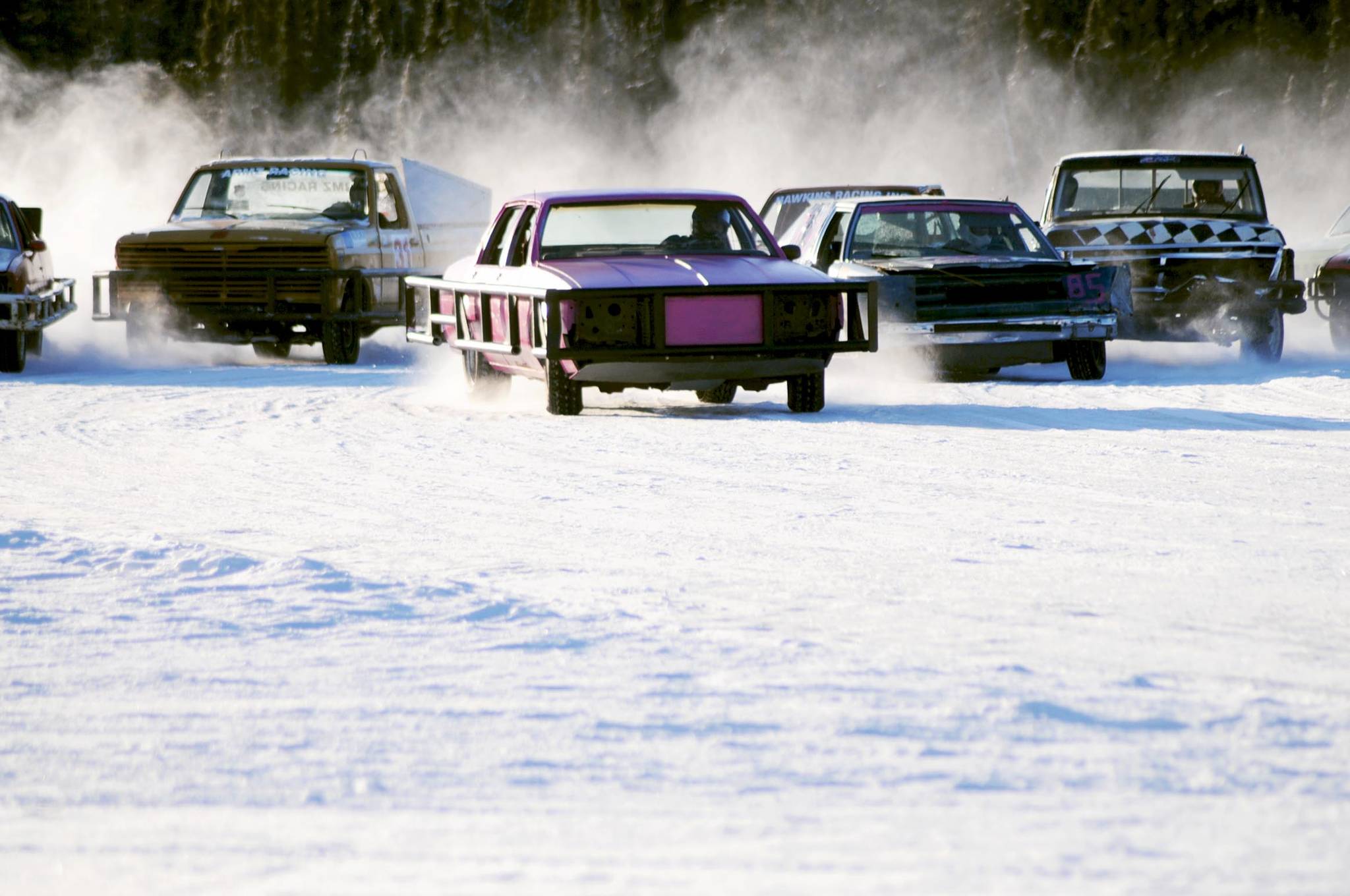 Drivers skid around one of the corners on the ice track atop a frozen lake at the Decanter Inn on Sunday, Jan. 22, 2018 in Kasilof, Alaska. Every Sunday in the winter, the Decanter Inn hosts Peninsula Ice Racing events for drivers to try their hand at the frozen track on the shallow lake at the bottom of the hill behind the inn. The racers can use studded tires on their front wheels only and equip the sides of their vehicles with bumpers as other vehicles are likely to slip and slide into them. Spinning out is common. A tow truck waits on the sidelines to retrieve drivers who get stuck on the berms alongside the track. Fans gathered Sunday despite the cold to cheer the racers on. The men race in the morning, followed by the women’s races in the afternoon. (Photo by Elizabeth Earl/Peninsula Clarion)