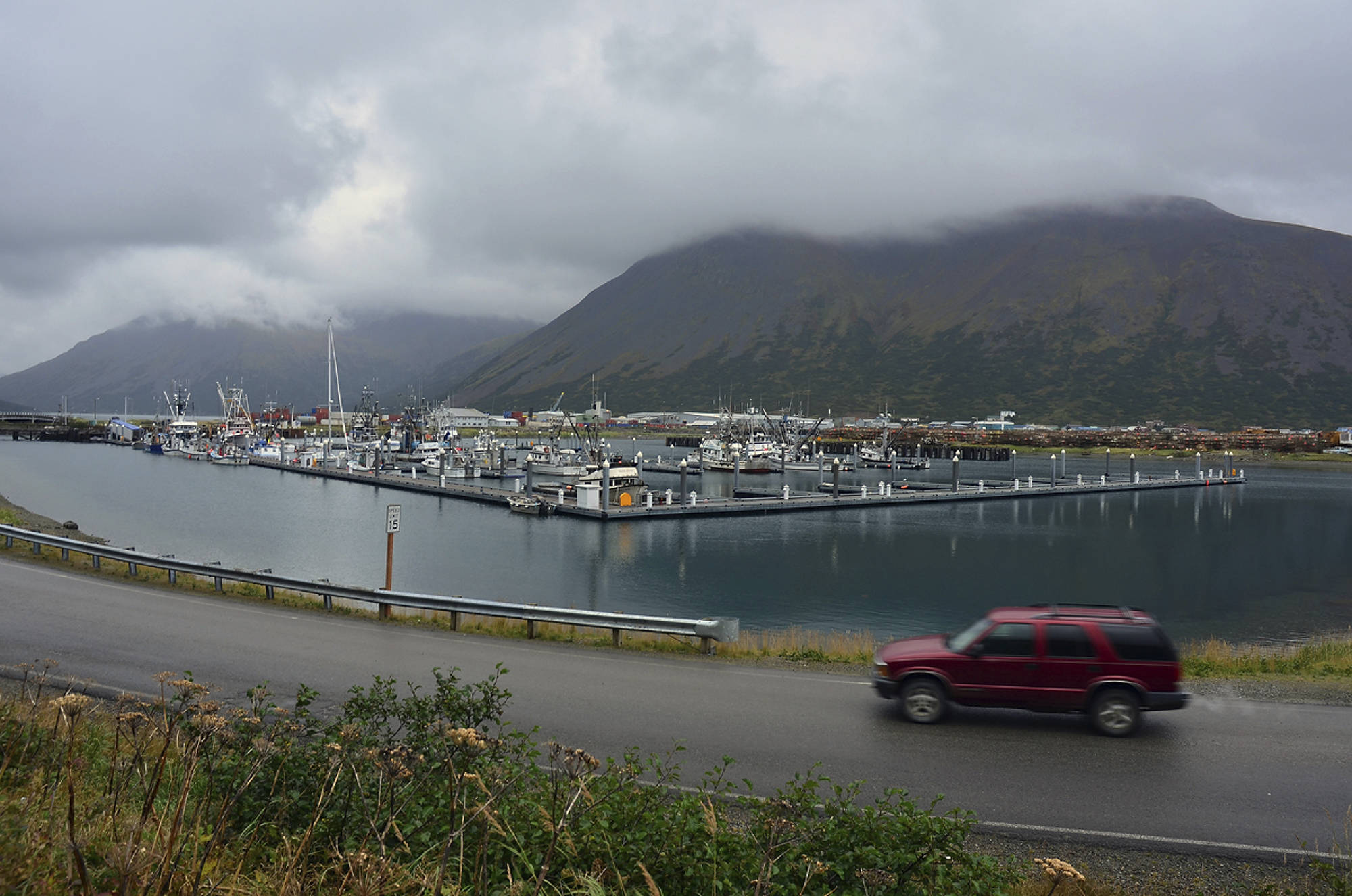 FILE - In this Sept. 23, 2013, file photo, a driver passes a small boat harbor in King Cove, Alaska. Interior Secretary Ryan Zinke signed a land exchange agreement Monday, Jan. 22, 2018, authorizing a swap of federal land in Izembek National Wildlife Refuge for land owned by King Cove Corporation that could lead to a road through the refuge so King Cove residents can have land access to an all-weather airport at Cold Bay, Alaska. (James Brooks/Kodiak Daily Mirror via AP, File)