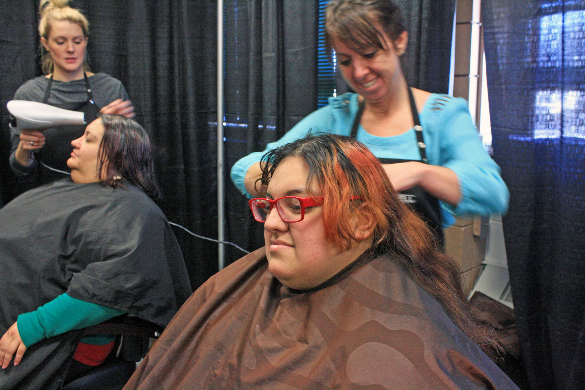 Calysta Lopez (right) and her mother Krissanna French receive haircuts at the Jan. 24 Project Homeless Connect at the Soldotna Regional Sports Complex. (Photo by Erin Thompson/Peninsula Clarion)