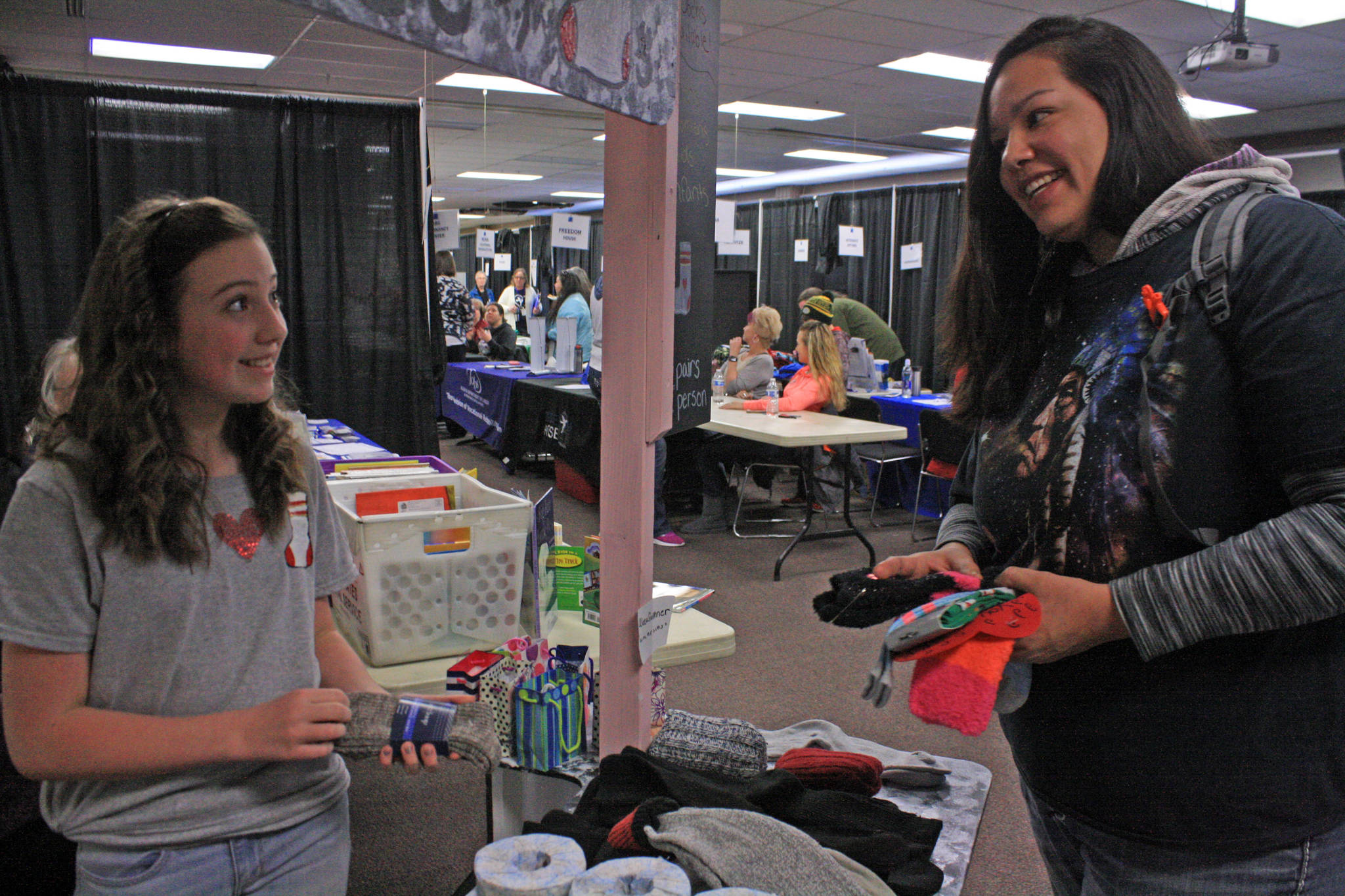 Aleea Faulkner, 12, shares socks with mom Wausaumoutouikwe Sandman-Shelifoe on Wednesday, Jan. 24 during Project Homeless Connect at the Soldotna Sports Complex. Faulkner spearheaded a sock drive to support the annual community service event. (Photo by Erin Thompson/Peninsula Clarion)