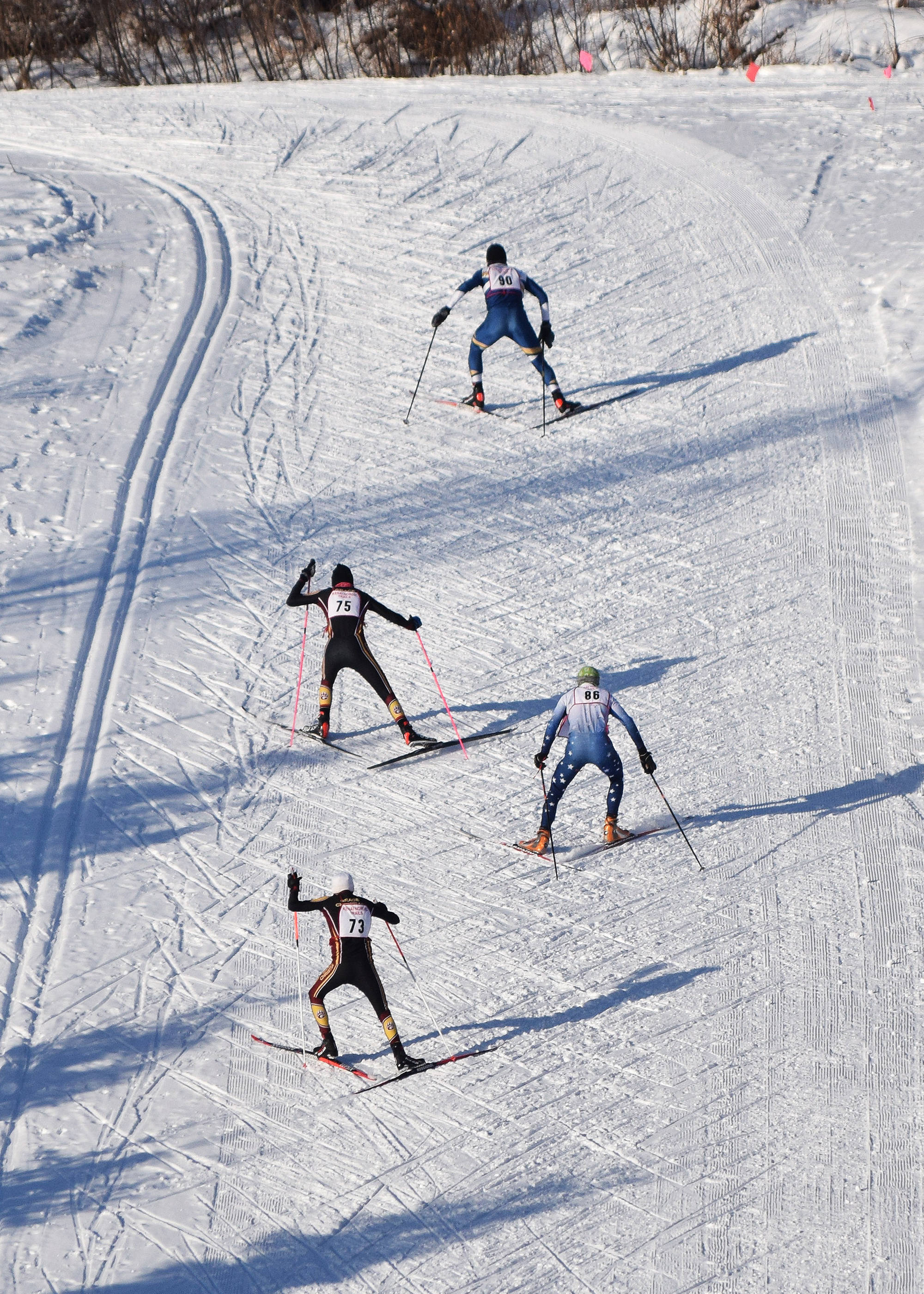 A group of skiers race up a hill late in the boys varsity race Friday afternoon in the Kenai Klassic races at the Tsalteshi Trails in Soldotna. (Photo by Joey Klecka/Peninsula Clarion)