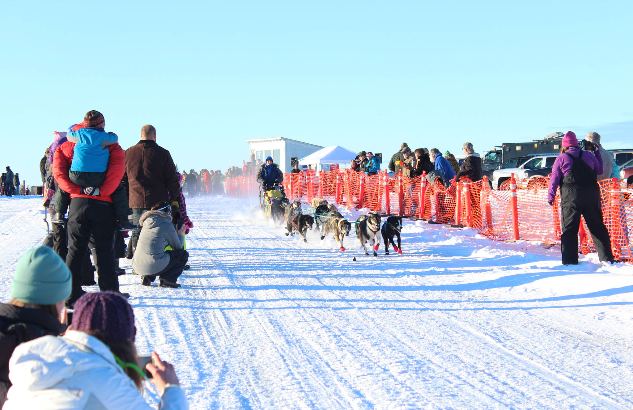 Onlookers line the race trail and snap photos as a sled dog team takes off from the starting line of the Tustumena 200 Sled Dog Race on Saturday, Jan. 27, 2018 at Freddie’s Roadhouse in Ninilchik, Alaska. The race, which returned last year after being canceled in 2014, 2015 and 2016, is a roughly 100-mile loop that mushers will complete twice before finishing back in Ninilchik. (Photo by Megan Pacer/Homer News)