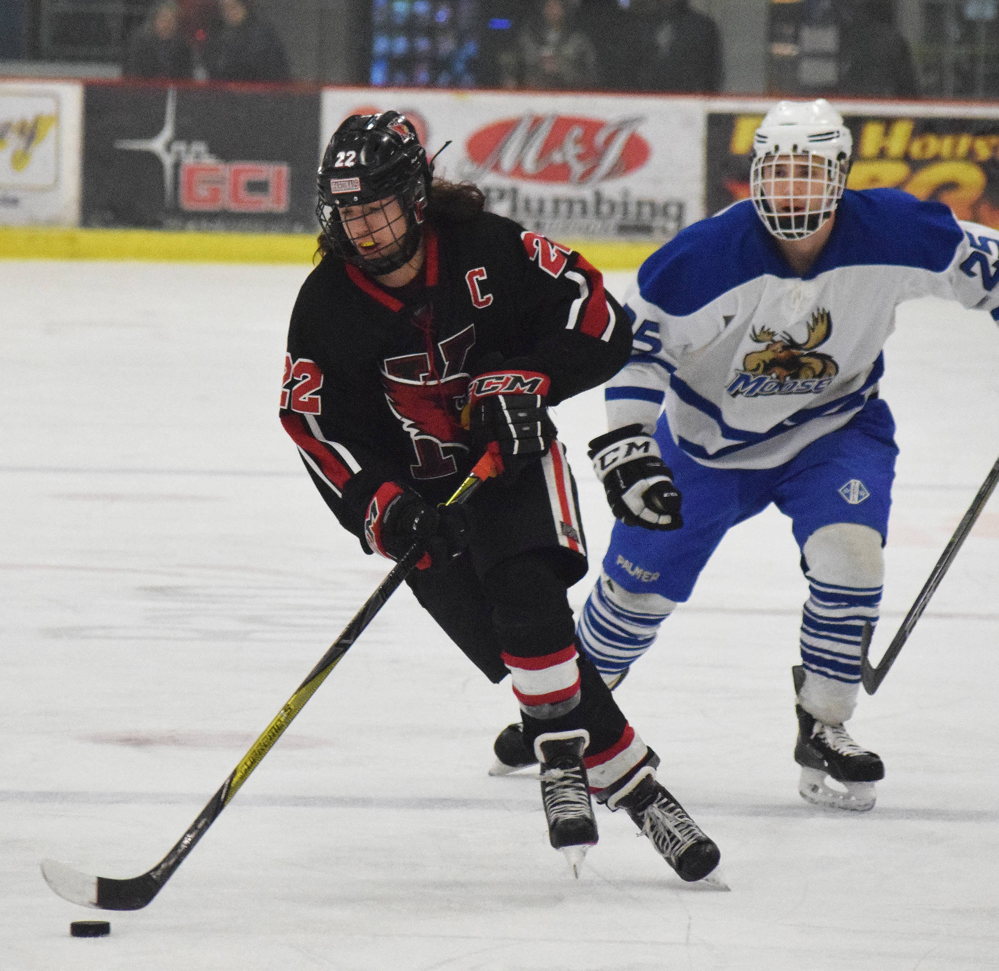 Kenai Central’s Matt Hagel (22) streaks down the ice in front of Palmer skater RJ Avezac Thursday evening in a North Star Conference tournament semifinal at the Soldotna Regional Sports Complex. (Photo by Joey Klecka/Peninsula Clarion)