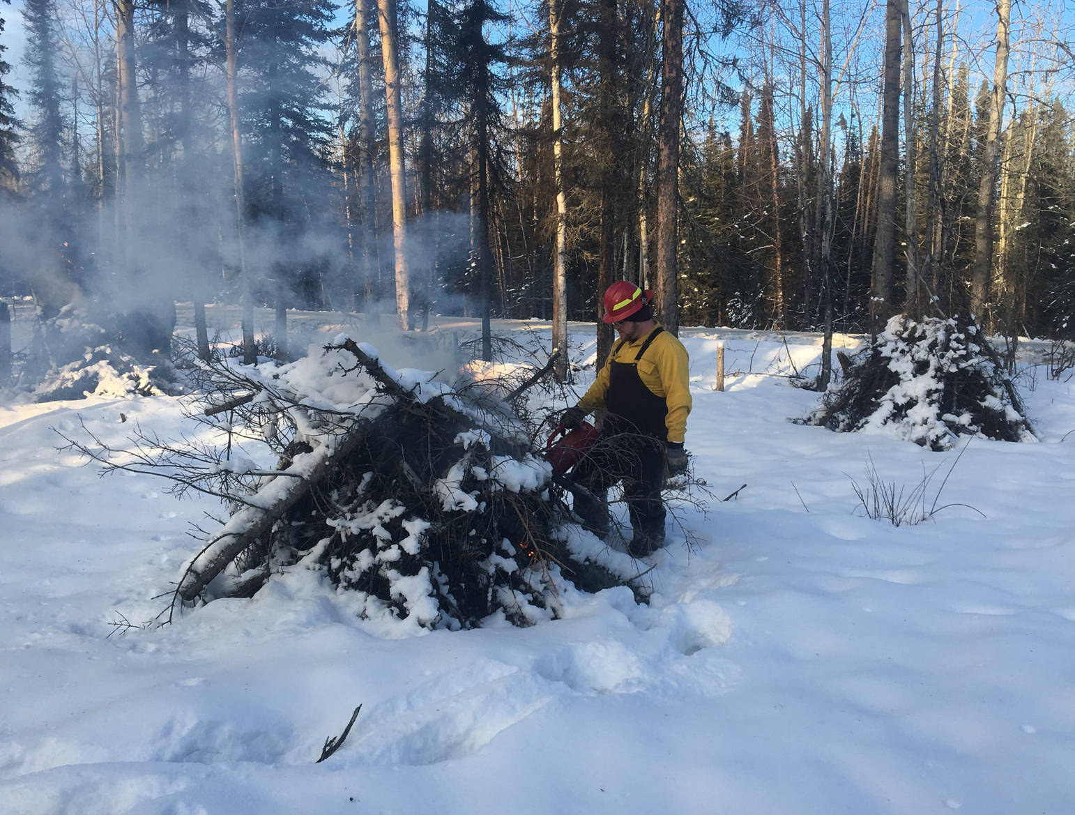 Using a drip torch to light piled vegetation and other burnable debris to reduce fuel loads along the wildland-urban interface on Funny River Road. (Photo courtesy Kenai National Wildlife Refuge)
