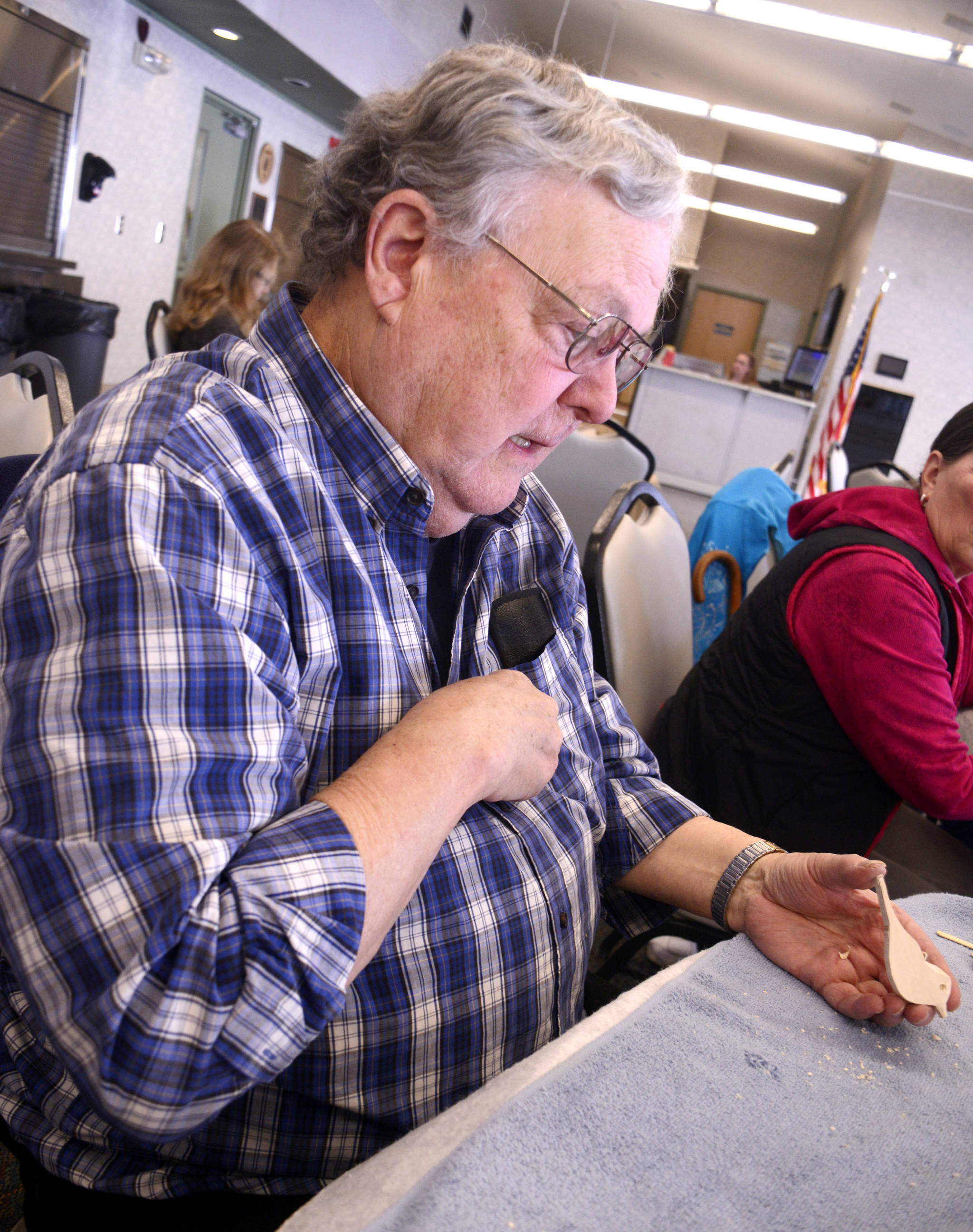 Del Otter leads a whittling lesson at the Kenai Senior Center in Kenai on Tuesday, guiding a class through the basics of carving a small bird magnet. (Photo by Kat Sorensen/Peninsula Clarion)