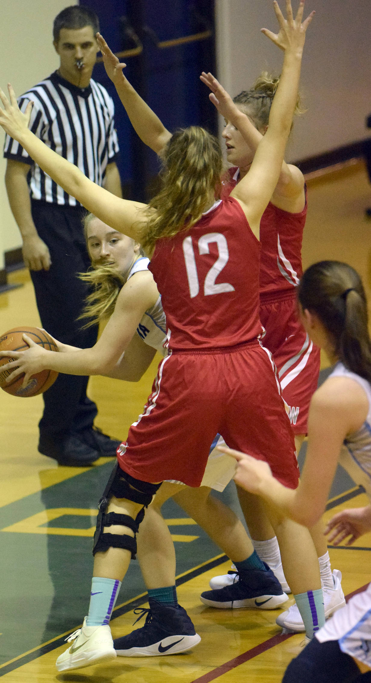 Soldotna’s Kalyn McGillivray passes around Wasilla’s Maclaren Obremski and Azlynn Brandenburg on Thursday, Feb. 15, 2018, at Soldotna High School. (Photo by Jeff Helminiak/Peninsula Clarion)