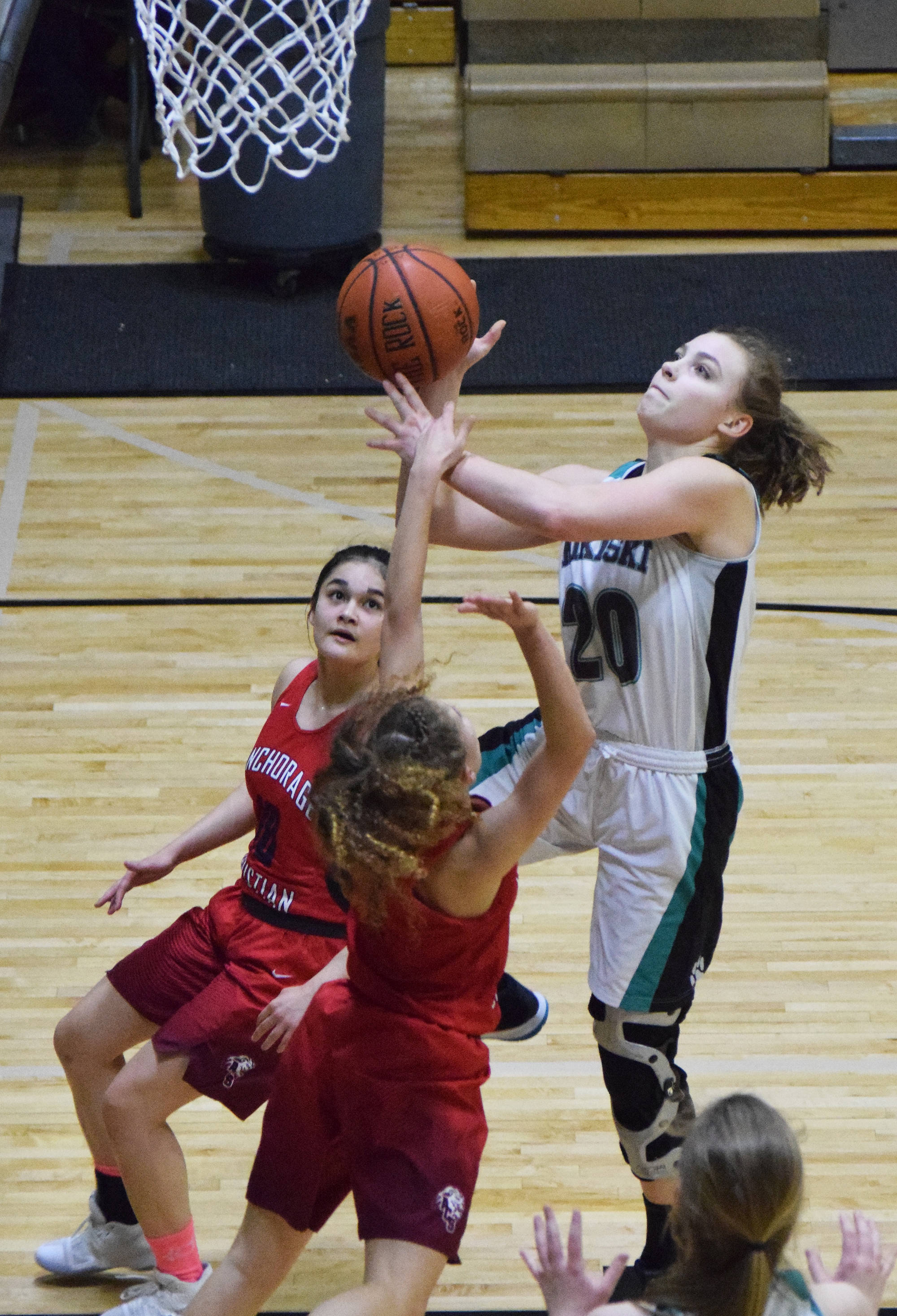 Nikiski’s Bethany Carstens drives for a layup over ACS defenders Mary Kate Parks (middle) and Jessie Davis Friday at Nikiski High School. (Photo by Joey Klecka/Peninsula Clarion)