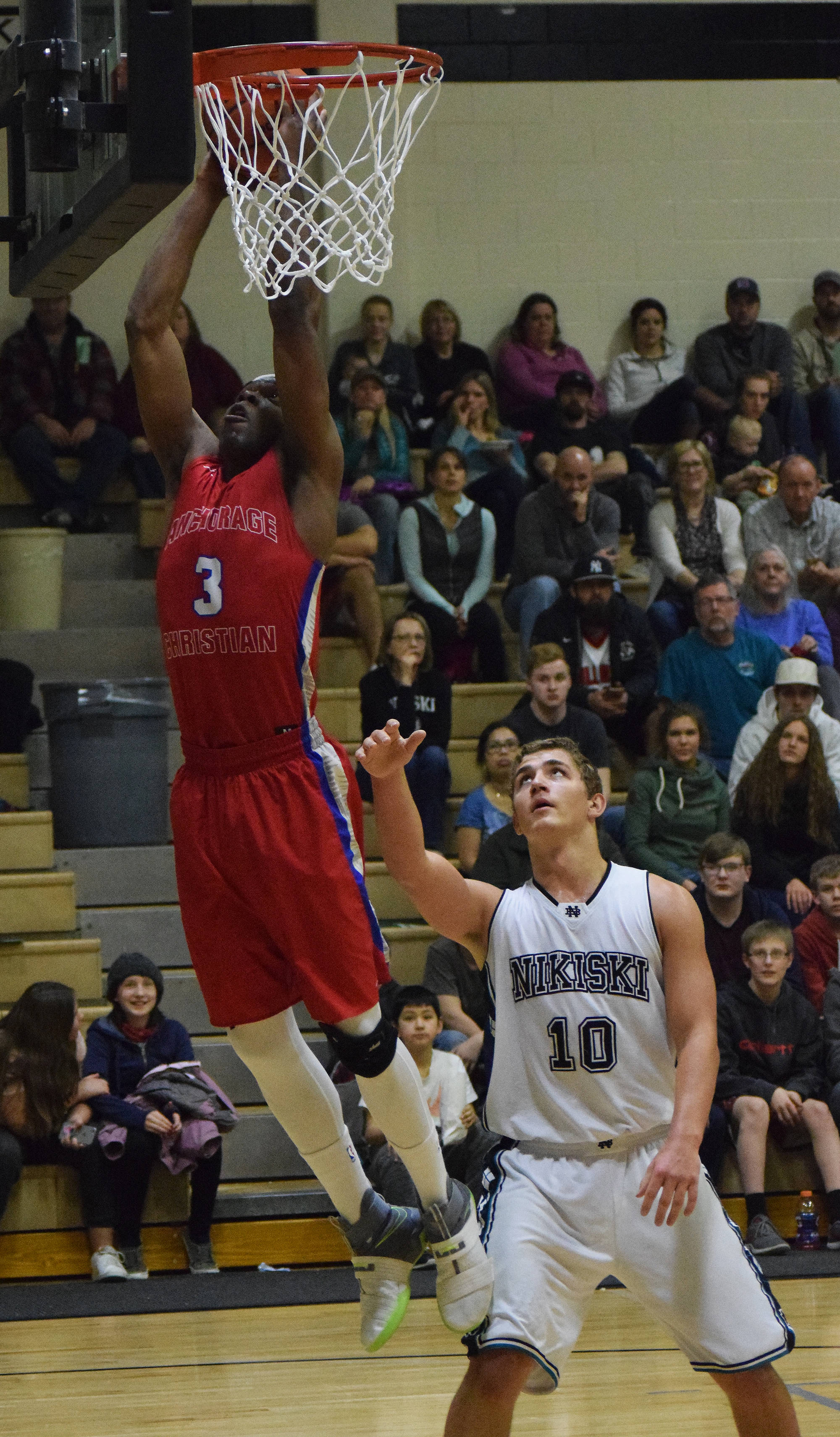 ACS forward Frederick Onochie lays in a bucket over Nikiski’s Ian Johnson (10) Friday at Nikiski High School. (Photo by Joey Klecka/Peninsula Clarion)