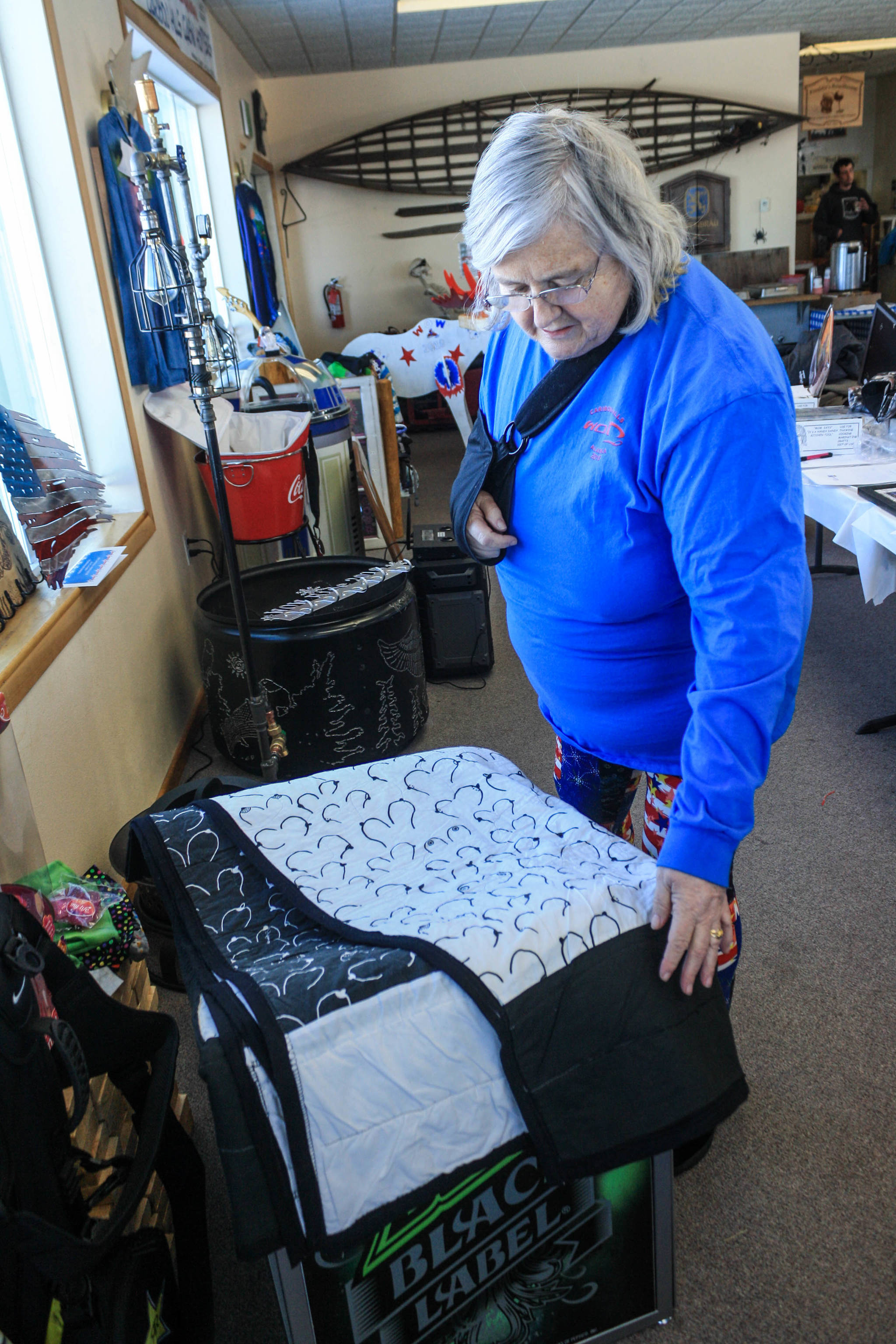 Kathy Lopeman, founder of the Way Out Women snowmachine ride fundraiser, shows off a quilt offered for auction at the Saturday, Feb. 24, 2018 event in the Caribou Hills near Ninilchik, Alaska. (Photo by Erin Thompson/Peninsula Clarion)