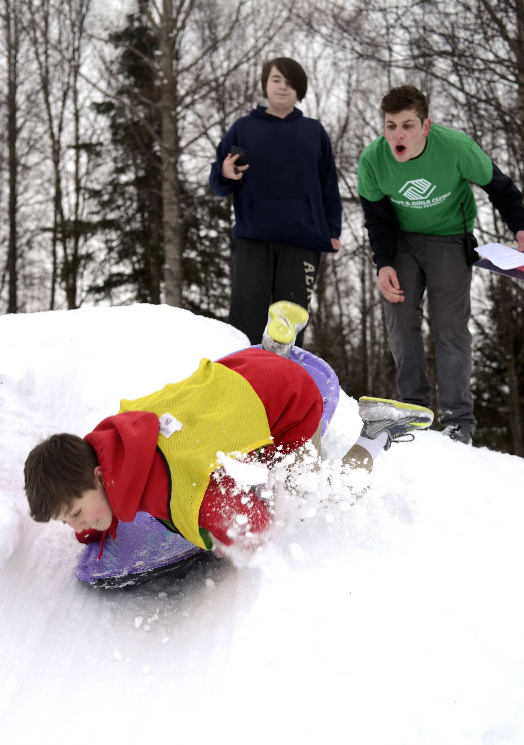 Boone Theiler wipes out during a sled race at the Boys and Girls Club in Kenai for the Police Athletic League Club on Monday. The club is a sports-oriented opportunity for youth and law enforcement to interact and organizers set-up an Olympics inspired day where the kids competed for medals in different winter activities. (Photo by Kat Sorensen/Peninsula Clarion)