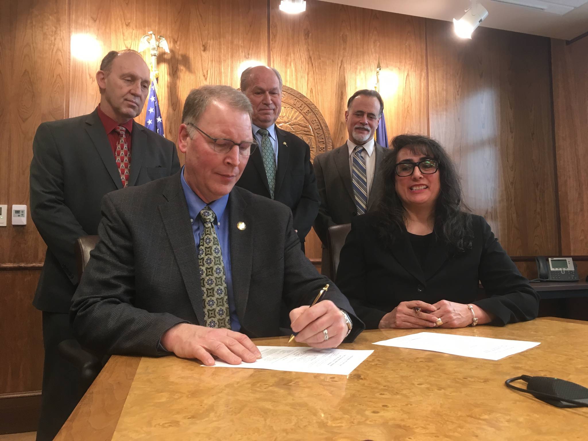 Alaska Department of Transportation and Public Facilities Commissioner Mark Luiken (front left) signs the final Environmental Impact Statement for the long-awaited Cooper Landing Bypass project as Federal Highway Administration Division Administrator Sandra Garcia-Aline (front right) and (back row, from left) Rep. Gary Knopp (R-Kenai), Gov. Bill Walker and Sen. Peter Micciche (R-Soldotna) look on Wednesday, March 7, 2018 in Juneau, Alaska. The Cooper Landing bypass, officially known as the Sterling Highway Milepost 45&