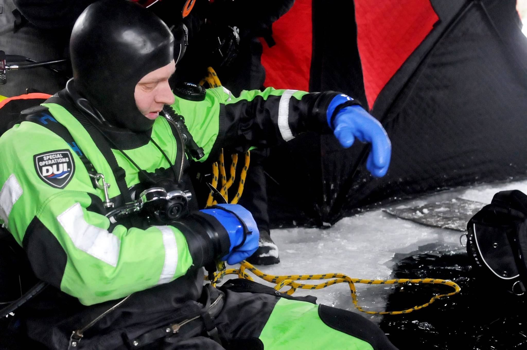Matt Quiner of the Nikiski Fire Department checks his gear before dropping through a hole in the ice covering Island Lake as part of a training drill Friday, March 9, 2018 in Nikiski, Alaska. The Nikiski Fire Department is working on bringing all the members of its ice diving team up to proper certifications. To attain full certifications, divers have to clock a number of hours in the water, including practicing beneath the ice. (Photo by Elizabeth Earl/Peninsula Clarion)