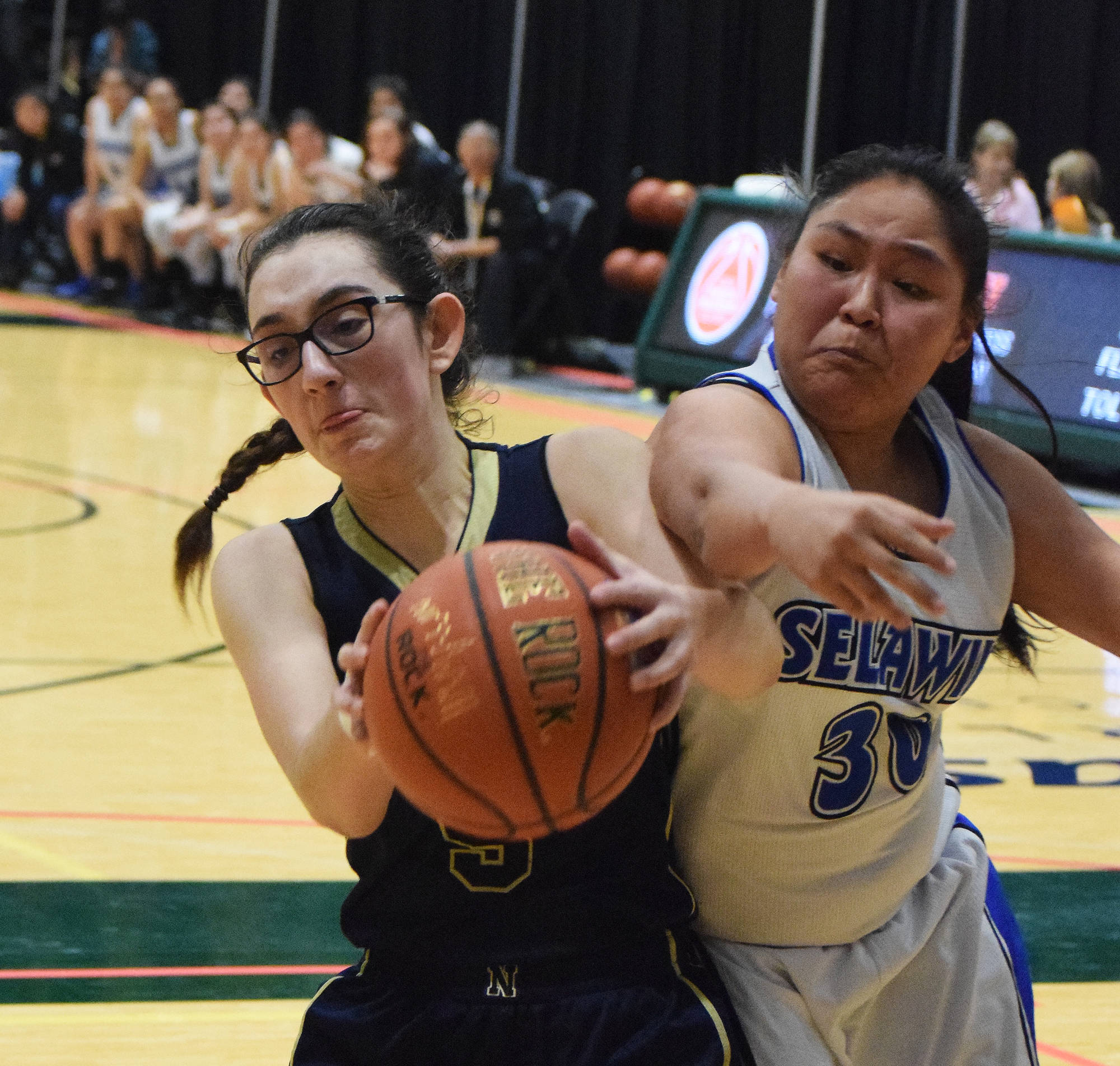 Ninilchik’s Olivia Delgado keeps the ball away from Selawik’s Kali Howarth Wednesday in an opening round contest at the Class 1A state basketball tournament at the Alaska Airlines Center in Anchorage. (Photo by Joey Klecka/Peninsula Clarion)