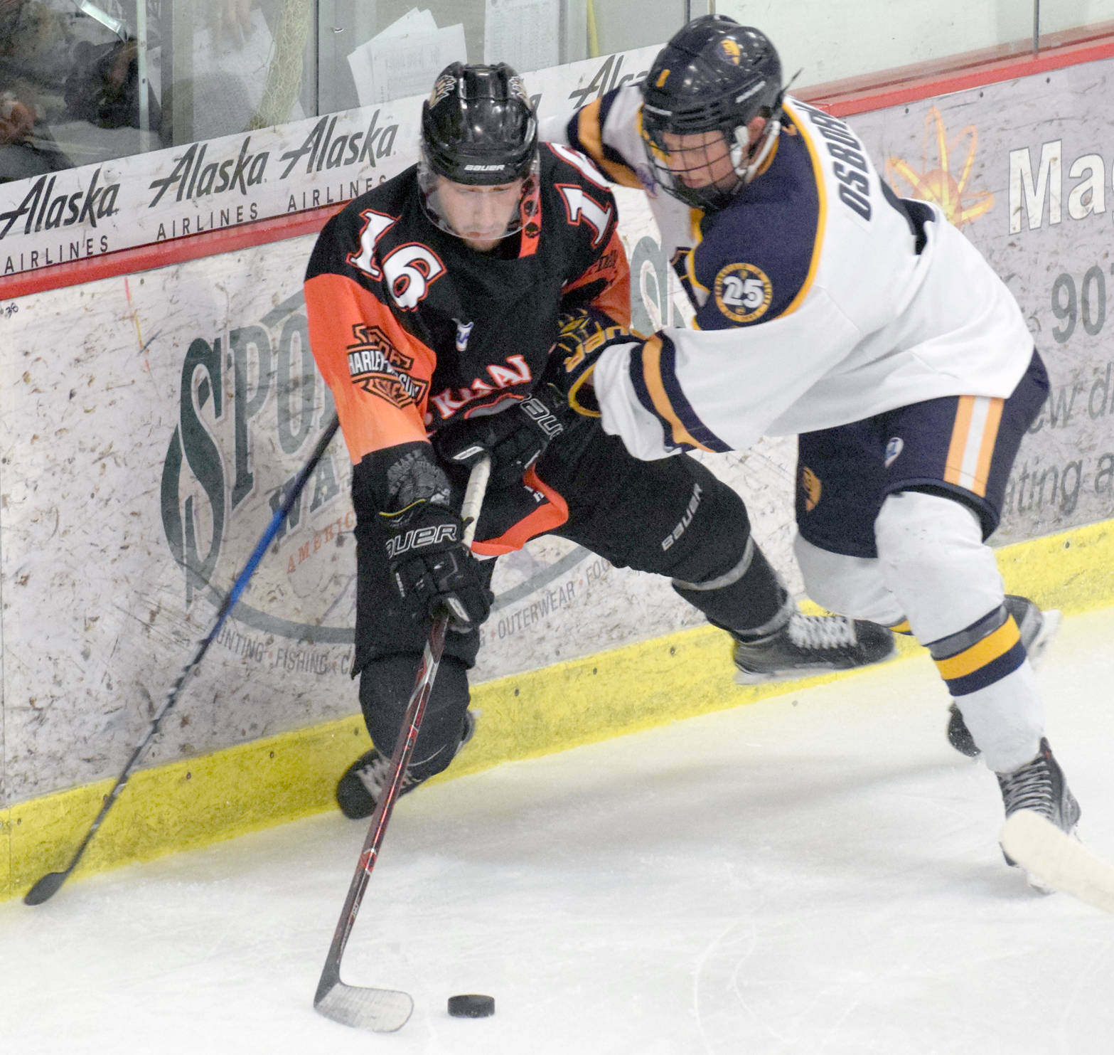 Kenai River Brown Bears forward David Kaplan shovels a pass out in front of the net against Springfield (Illinois) Jr. Blues defenseman Max Osborne on Friday at the Soldotna Regional Sports Complex. (Photo by Jeff Helminiak/Peninsula Clarion)
