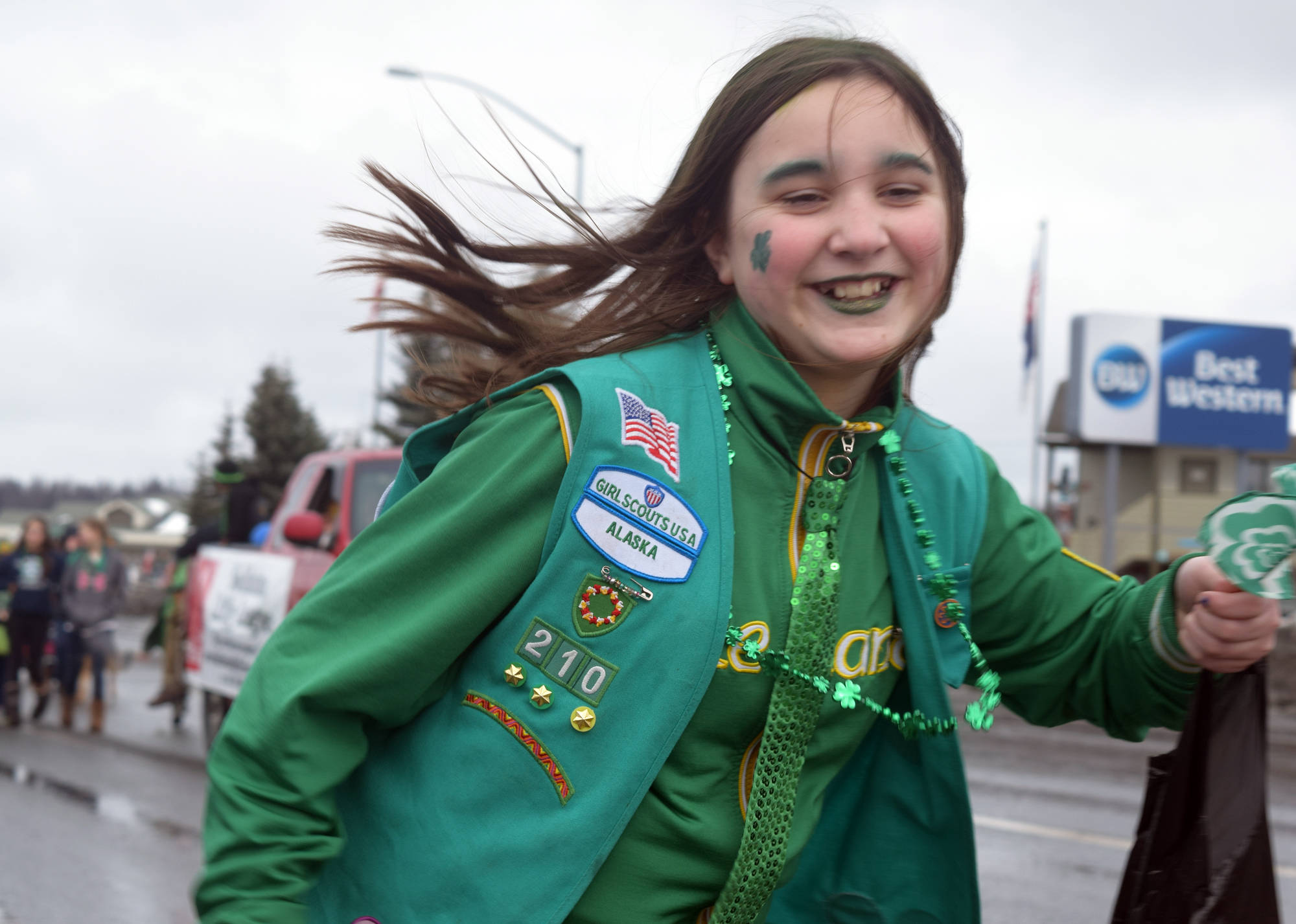 Caitlyn Crapps of Kenai runs along the St. Patrick’s Day parade route while marching with her girl scouts troop Saturday, March 17. (Photo by Kat Sorensen/Peninsula Clarion)