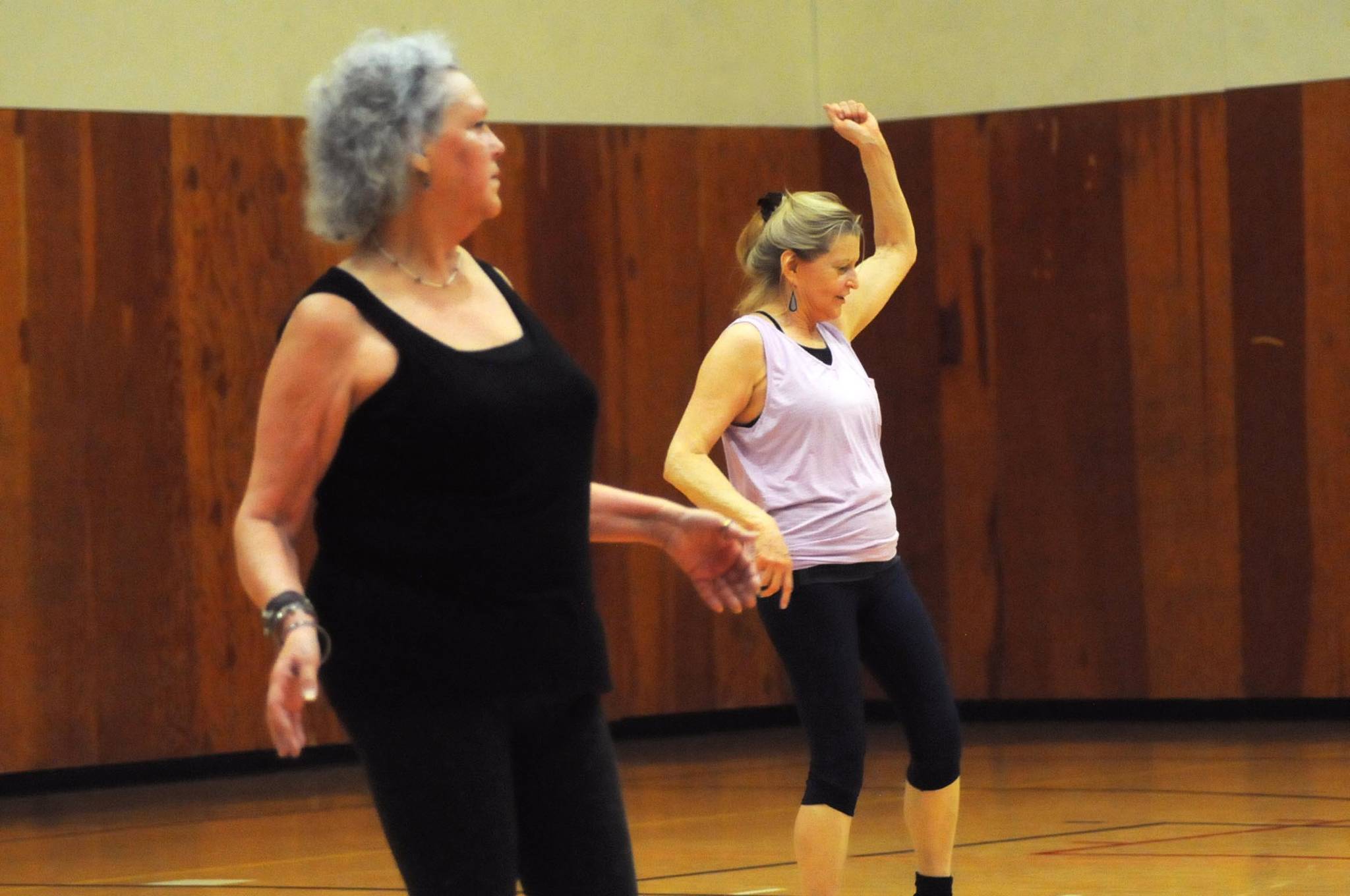 Sallie Macy (right) and Glenna Hudson (left), students in Truman Krogel’s Zumba Gold class, follow the steps to a song during a class at the Kenai Recreation Center on Thursday, March 15, 2018 in Kenai, Alaska. Krogel, 74, said he first tried Zumba himself four years ago, loved it and began teaching classes of his own in January 2017. (Photo by Elizabeth Earl/Peninsula Clarion)