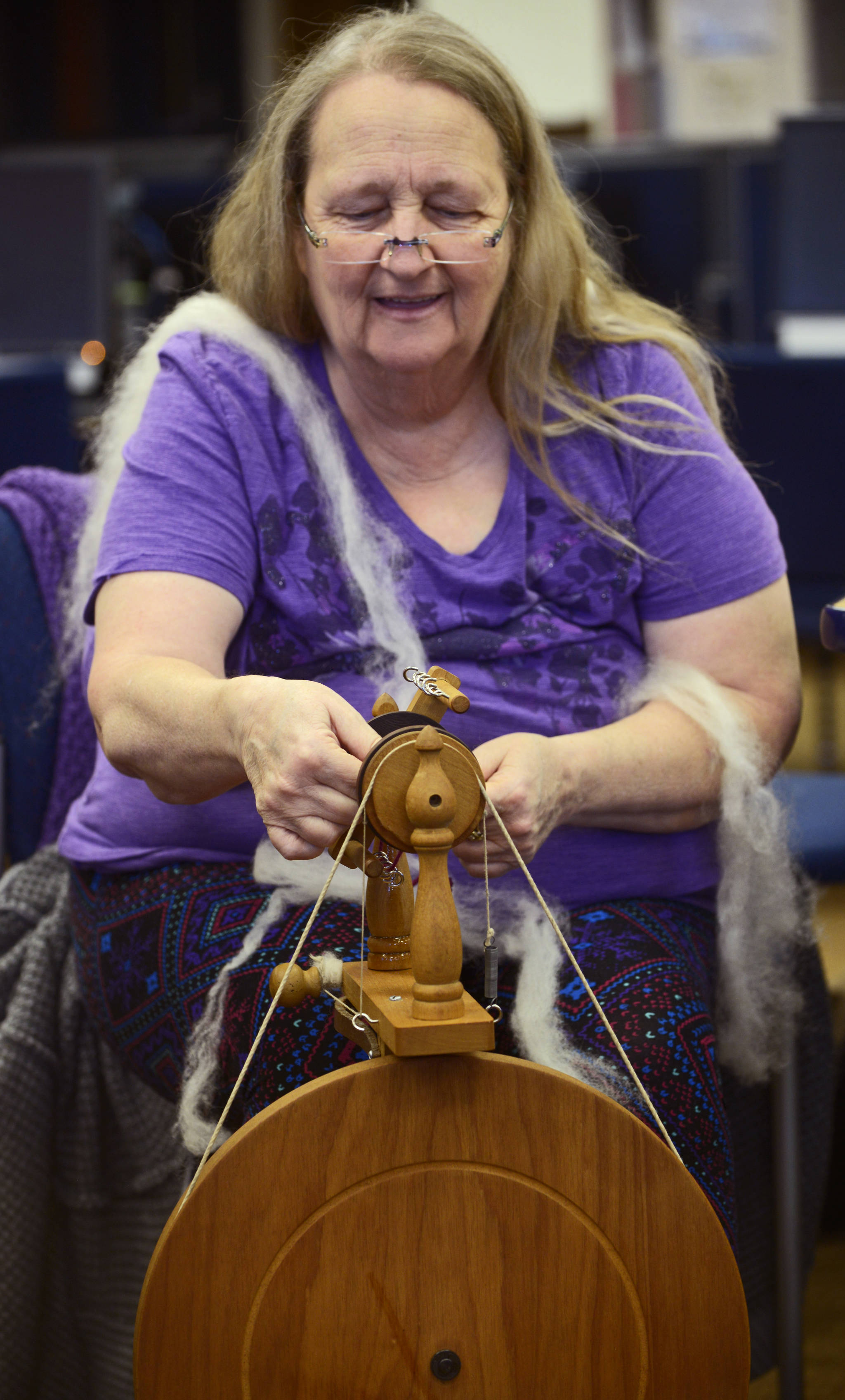 Debora Meester adjusts the bobbin of a spinning wheel while spinning wool into yarn during the first session of the Soldotna Community Schools yarn-spinning class on Tuesday, March 20 in the library of the Soldotna Preparatory School in Soldotna, Alaska. (Ben Boettger/Peninsula Clarion)