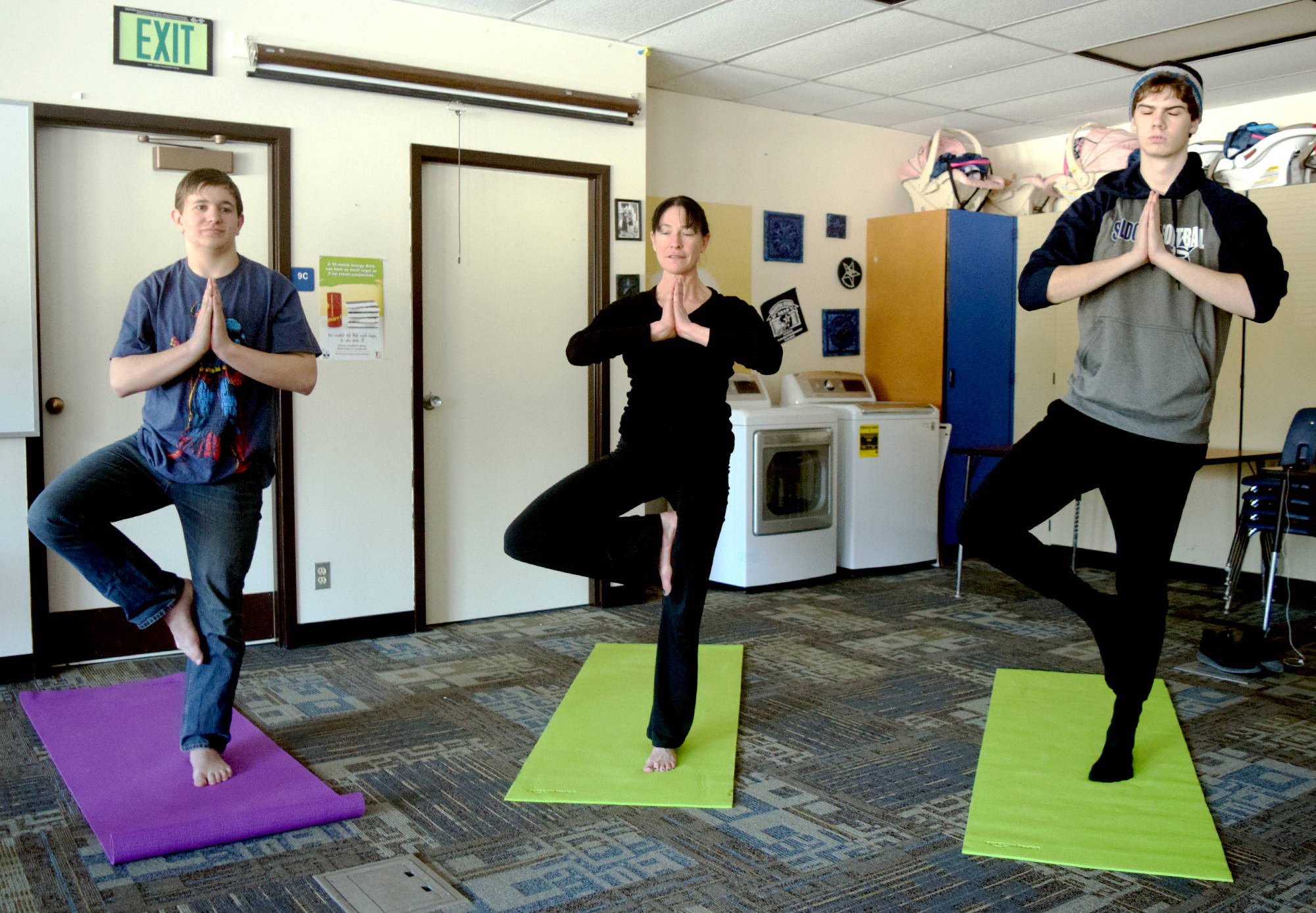 Lisa Wells, center, leads a group of students into tree pose during a yoga class held at Soldotna High School on Friday. (Photo by Kat Sorensen/Peninsula Clarion)