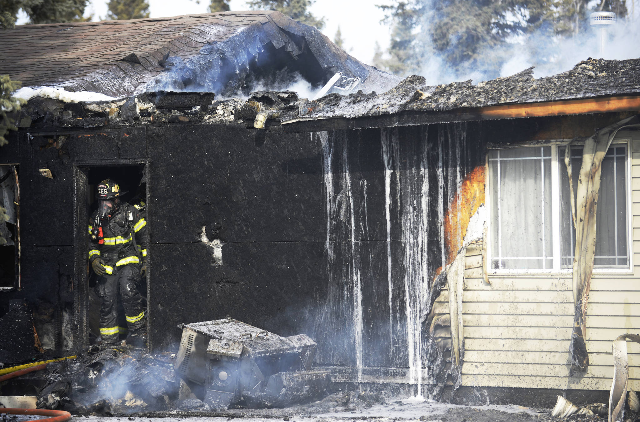 A Central Emergency Services firefighter emerges from a burning home on Tuesday, April 3, 2018 off of Poppy Lane near Kalifornsky Beach Road. (Ben Boettger/Peninsula Clarion) 