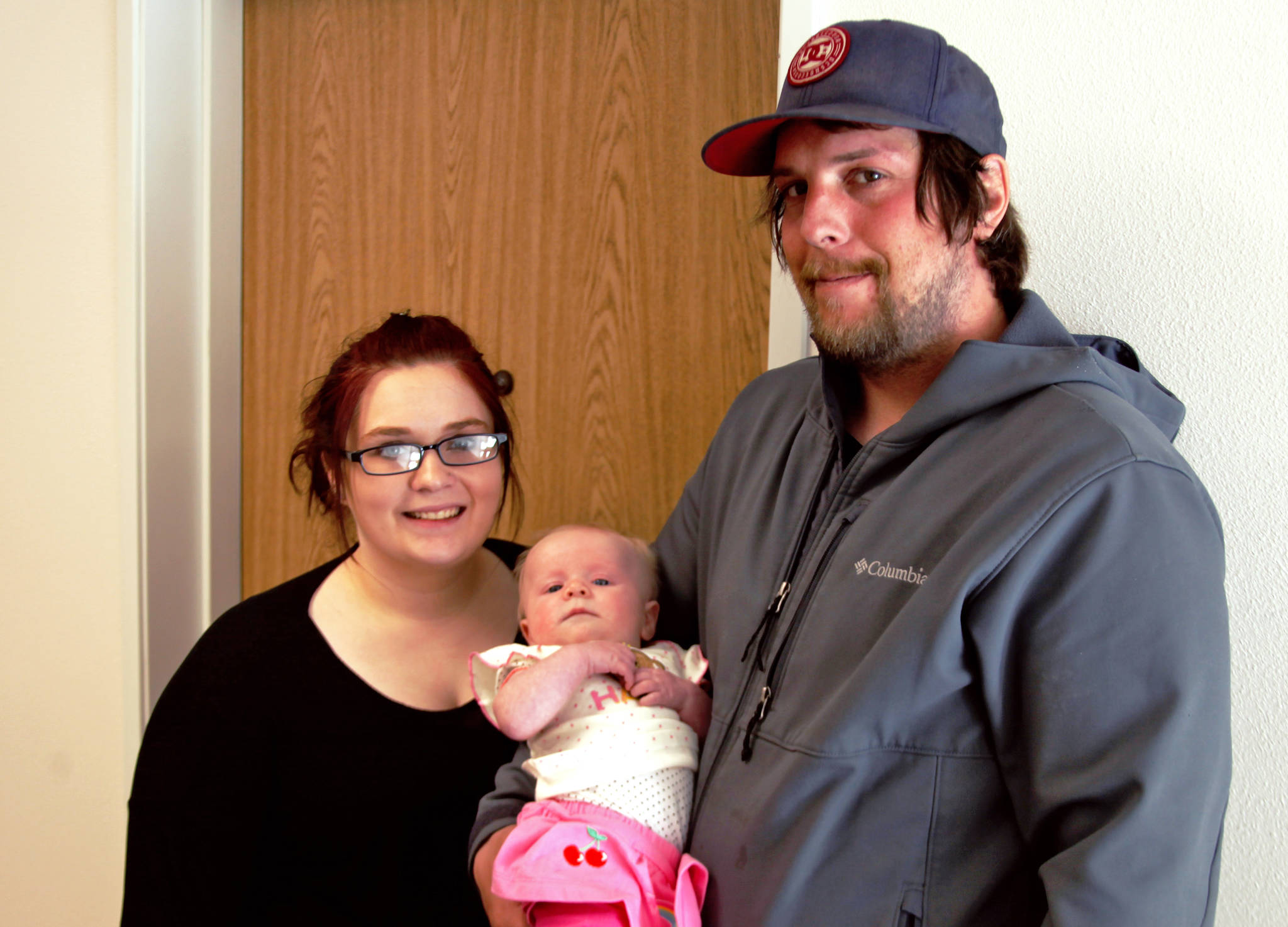 Alycia Backstrom (left) and Steven Taylor pose with infant Bailey Backstrom outside their rooms in Kenai’s new Clear Pointe six-plex — the city’s first income-restricted rental housing, constructed by the Homer-based not-for-profit Kenai Housing Initiative — on Wednesday, April 4, 2018 in Kenai, Alaska. After a roughly two-month search for a place to live, Taylor and Backstrom became Clear Pointe’s first tennants after moving in Monday. (Ben Boettger/Peninsula Clarion)