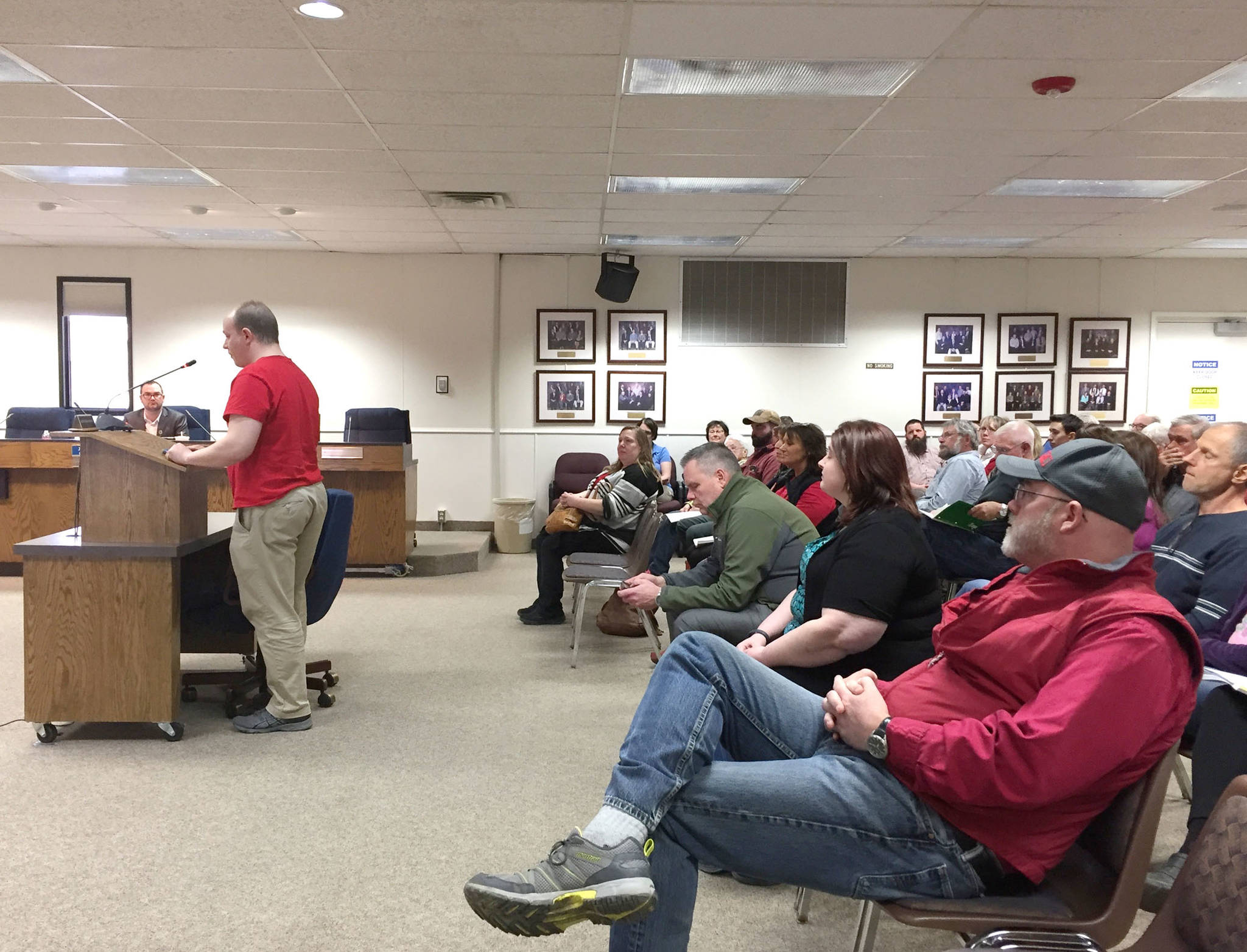 Kindergarten teacher Daniel Bowen (at podium) speaks to the Kenai Peninsula Borough Assembly in favor of full funding for the Kenai Peninsula Borough School District at the assembly’s meeting on Tuesday, April 3, 2018 in Soldotna, Alaska. About 40 people attended the meeting Tuesday, many wearing red, to show their support for public education funding. (Photo by Elizabeth Earl/Peninsula Clarion)