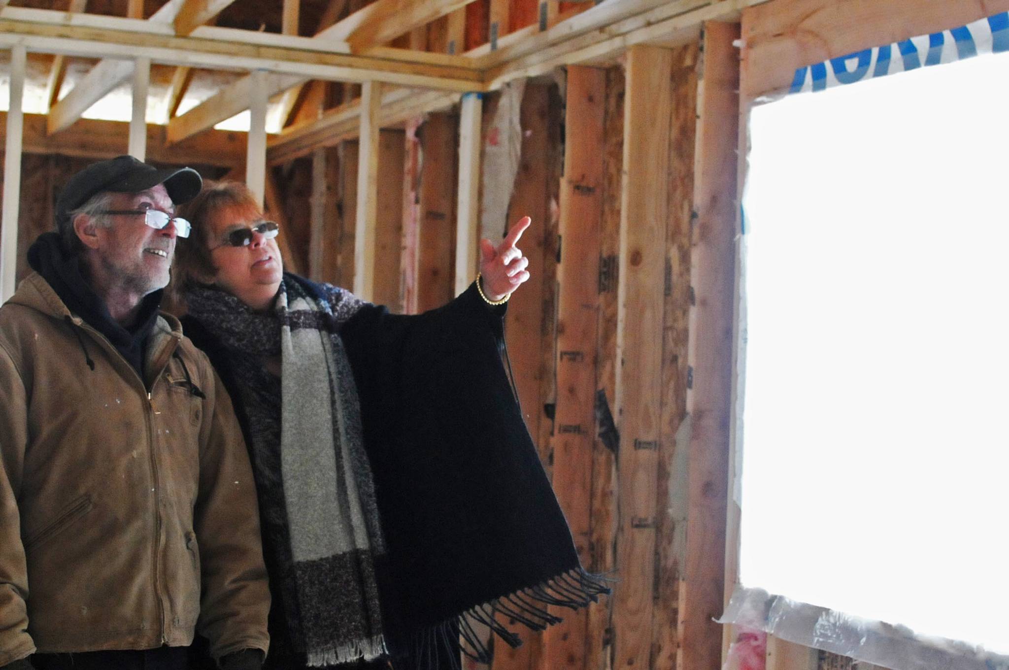 Contractor Ward Adams (left) and Nikiski resident Kimbra Mensch chat inside the shell of her home on Friday, March 9, 2018 in Nikiski, Alaska. Mensch, who moved to Nikiski from Wasilla, engaged a contractor to build her a home on Cabin Lake but is now having to tear it down because of mistakes in the construction. (Photo by Elizabeth Earl/Peninsula Clarion)