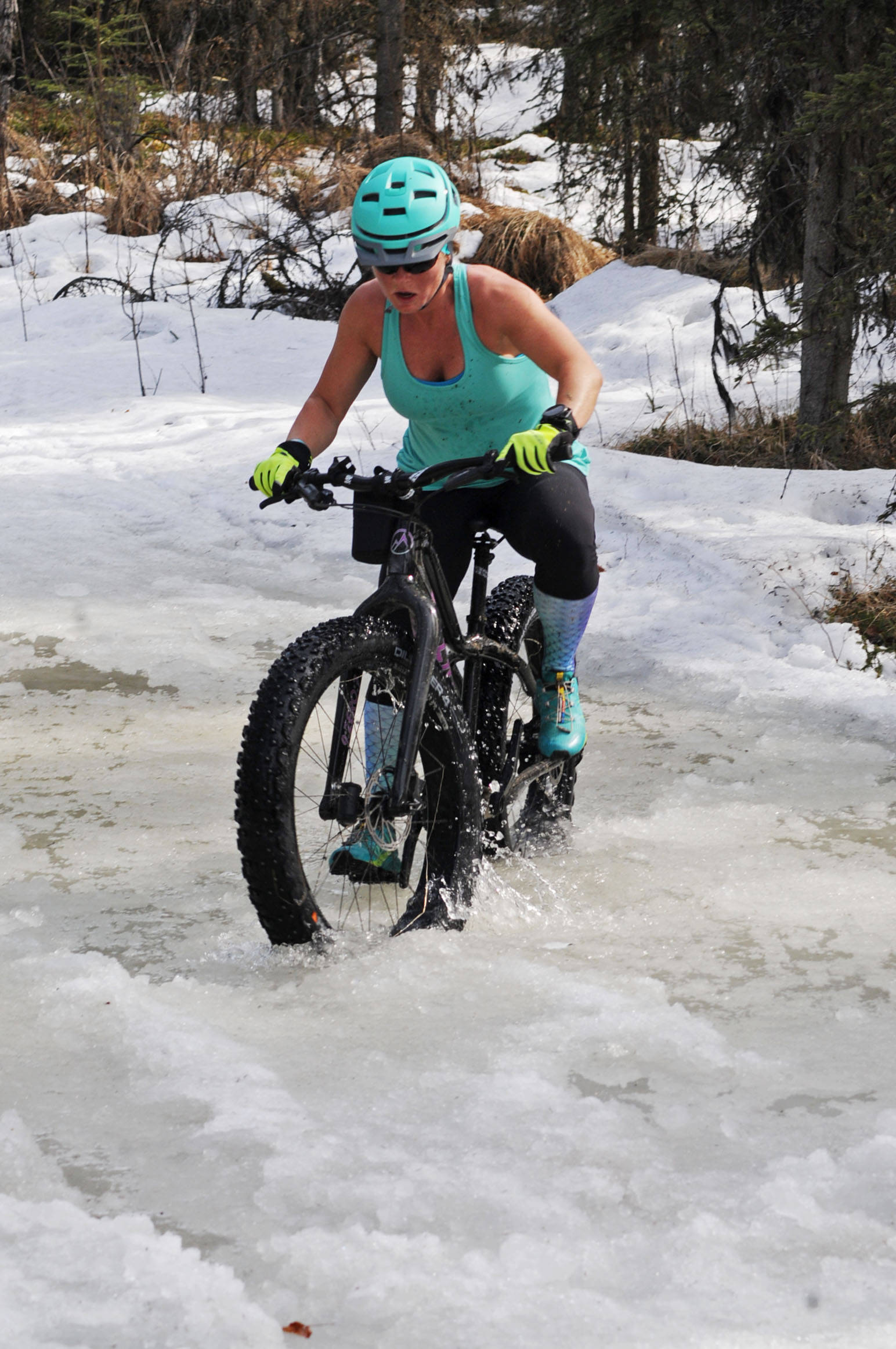Morgan Aldridge of Sterling navigates her fatbike through a deep icy puddle on the Wolverine Trail during the 2018 Choose Your Weapon race at Tsalteshi Trails on Sunday, April 15, 2018 in Soldotna, Alaska. Racers completed two 5-kilometer laps around the lower trails by running, biking or skiing, with the option of switching between laps for extra points. Most of the trails had some snow with patches of wet mud sprinkled throughout as spring temperatures begin to dominate the central Kenai Peninsula. (Photo by Elizabeth Earl/Peninsula Clarion)