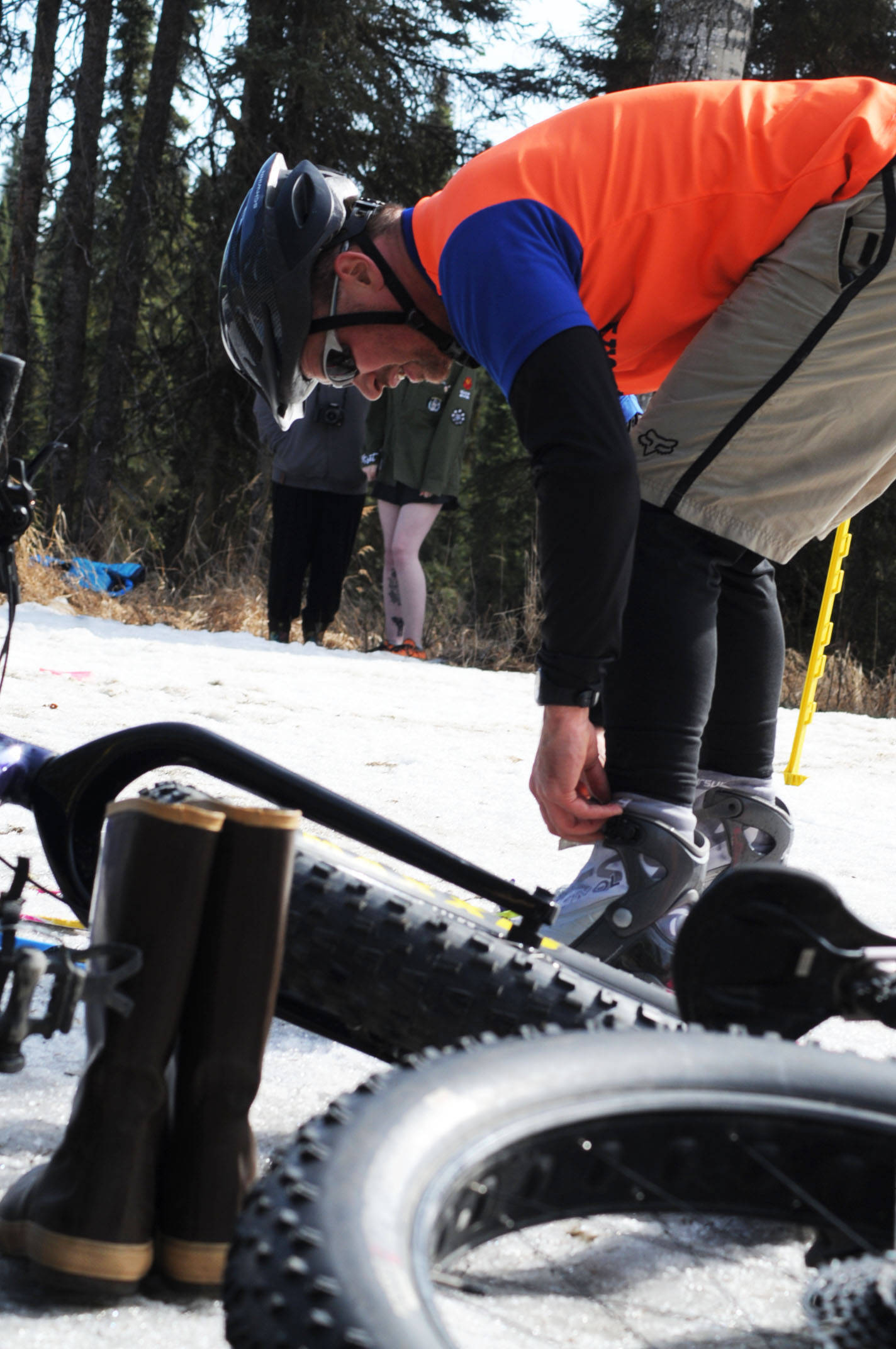 Anthony Murray swaps out his ski boots for Xtratuffs on the Wolverine Trail during the 2018 Choose Your Weapon race at Tsalteshi Trails on Sunday, April 15, 2018 in Soldotna, Alaska. Racers completed two 5-kilometer laps around the lower trails by running, biking or skiing, with the option of switching between laps for extra points. Most of the trails had some snow with patches of wet mud sprinkled throughout as spring temperatures begin to dominate the central Kenai Peninsula. Murray later said he was grateful for the Xtratuffs when navigating through an icy puddle up to his mid-calf. (Photo by Elizabeth Earl/Peninsula Clarion)