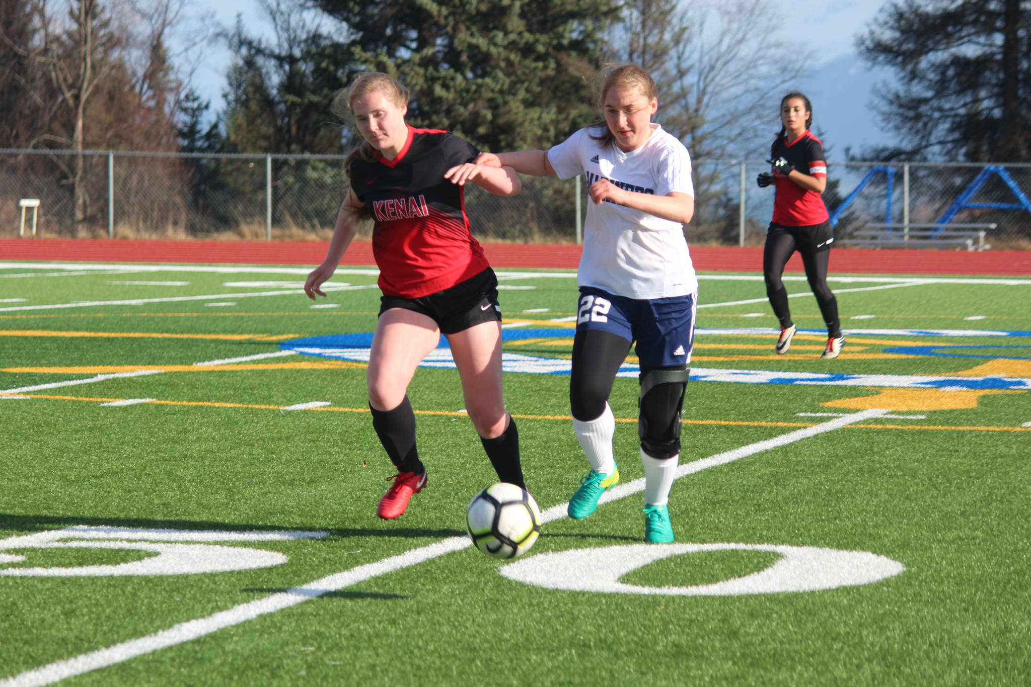 Homer’s Brenna McCarron battles with Kenai’s Julia Hanson to reach the ball first during their game Tuesday, April 24, 2018 in Homer, Alaska. The Mariners beat the Kardinals 1-0. (Photo by Megan Pacer/Homer News)