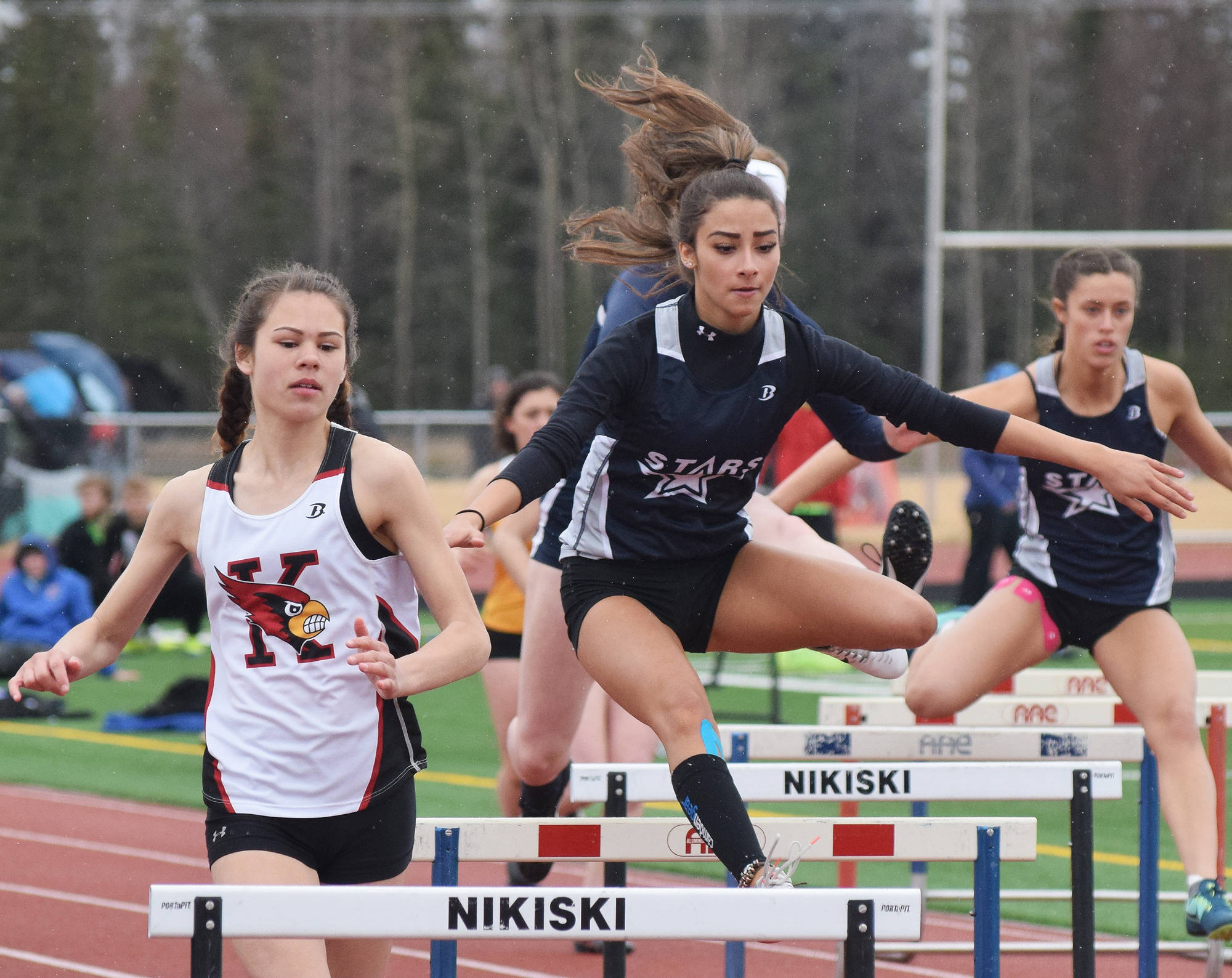 Soldotna sophomore Holleigh Jaime and Kenai sophomore Savannah Wilson tackle a hurdle in the girls 300-meter final Saturday at the Kenai Invitational at Ed Hollier Field. (Photo by Joey Klecka/Peninsula Clarion)