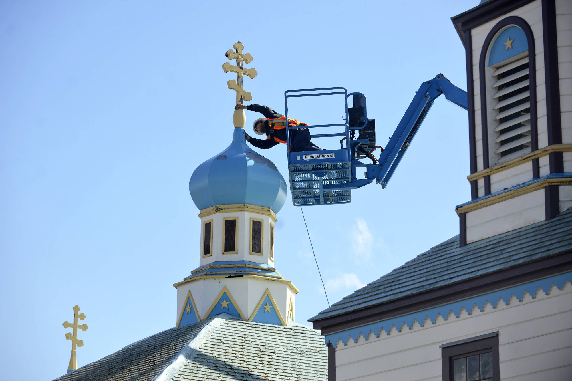 Glenn Beckmann of Rainproof Roofing inspects a weathered and tilting cross atop Kenai’sHoly Assumption of the Virgin Mary Russian Orthodox Church before removing it on Friday, May 4, 2018. Dorothy Gray , a Holy Assumption member and treasurer of the preservation nonprofit Russian Orthodox Sacred Sites in Alaska, said the church is now looking for local craftspeople interested in making replacements for the three old crosses. (Ben Boettger/Peninsula Clarion)