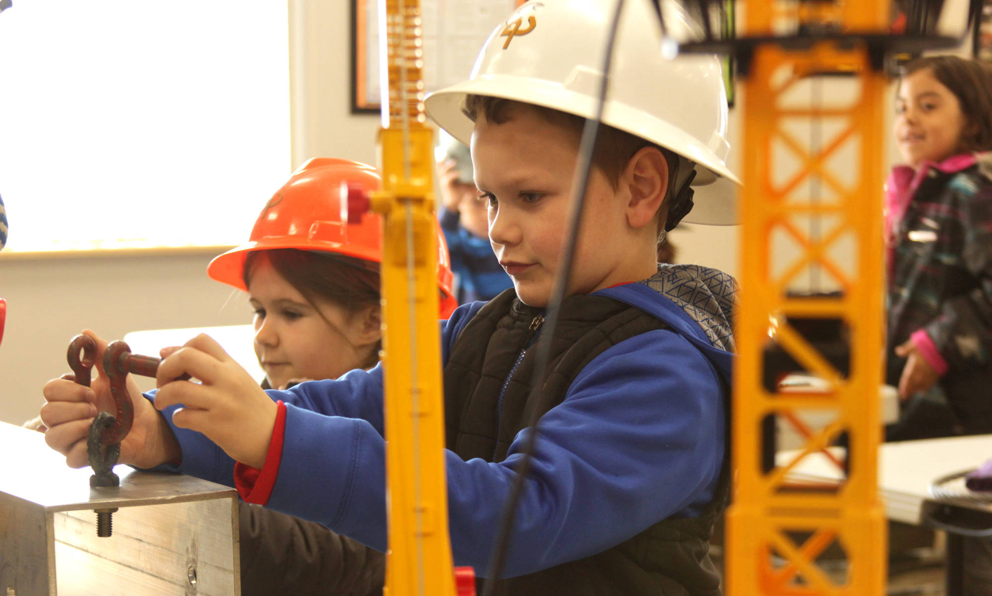 Kalifornsky Beach Elementary first-graders Maddi Redder (left) and Brayden Gregory prepare to rig a beam to a shop crane during their class’ field trip to Alaska Crane Consultants on Monday, May 7, 2018 on Kalifornsky Beach road. (Ben Boettger/Peninsula Clarion)