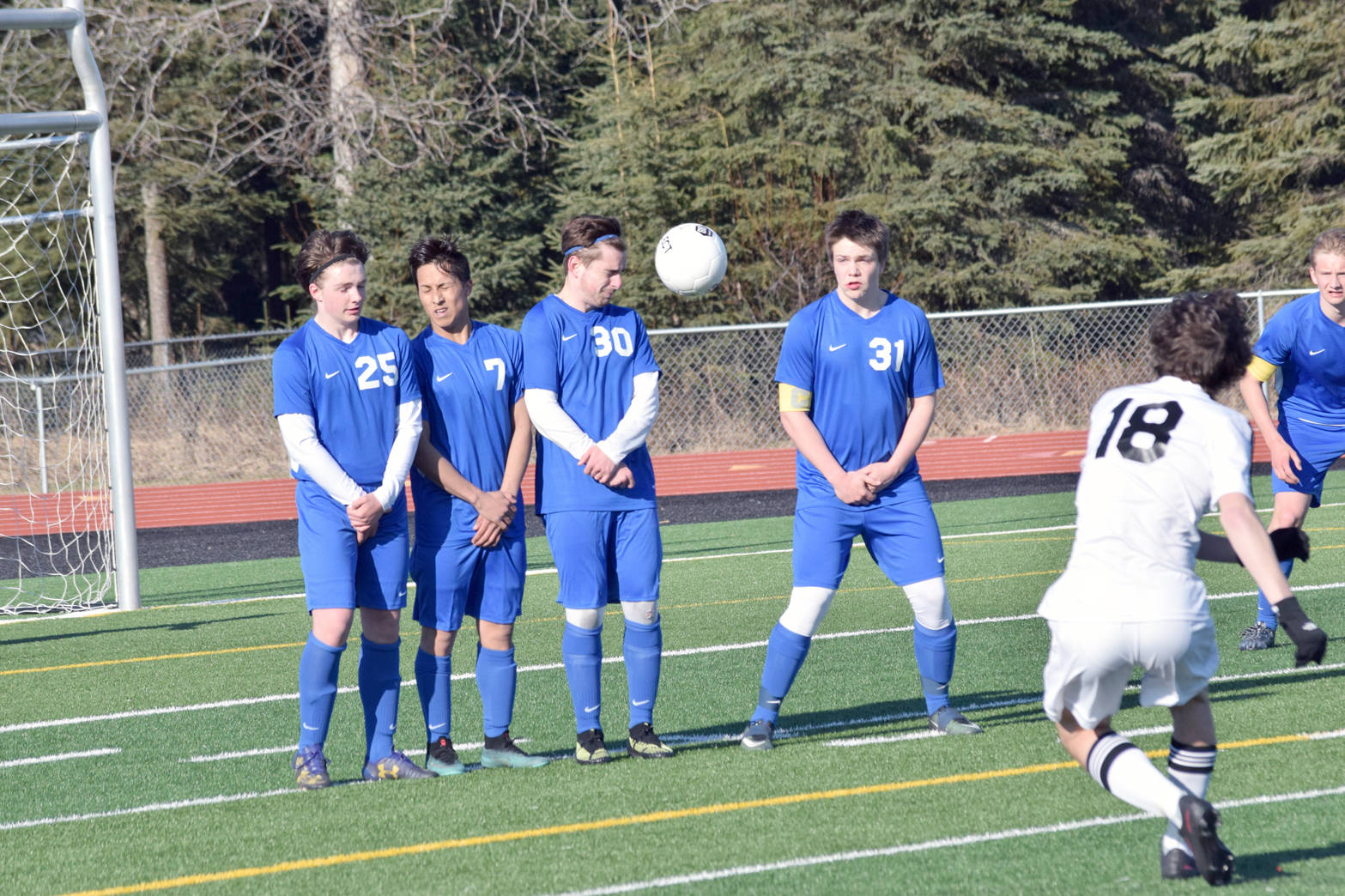 Kenai Central’s Damien Redder successfully avoids the wall of Soldotna’s Cameron Johnson, Sean McMullen, Ethan Bott and Eli Sheridan, but can’t convert a free kick Tuesday, May 1, 2018, at Kenai Central High School. (Photo by Jeff Helminiak/Peninsula Clarion)