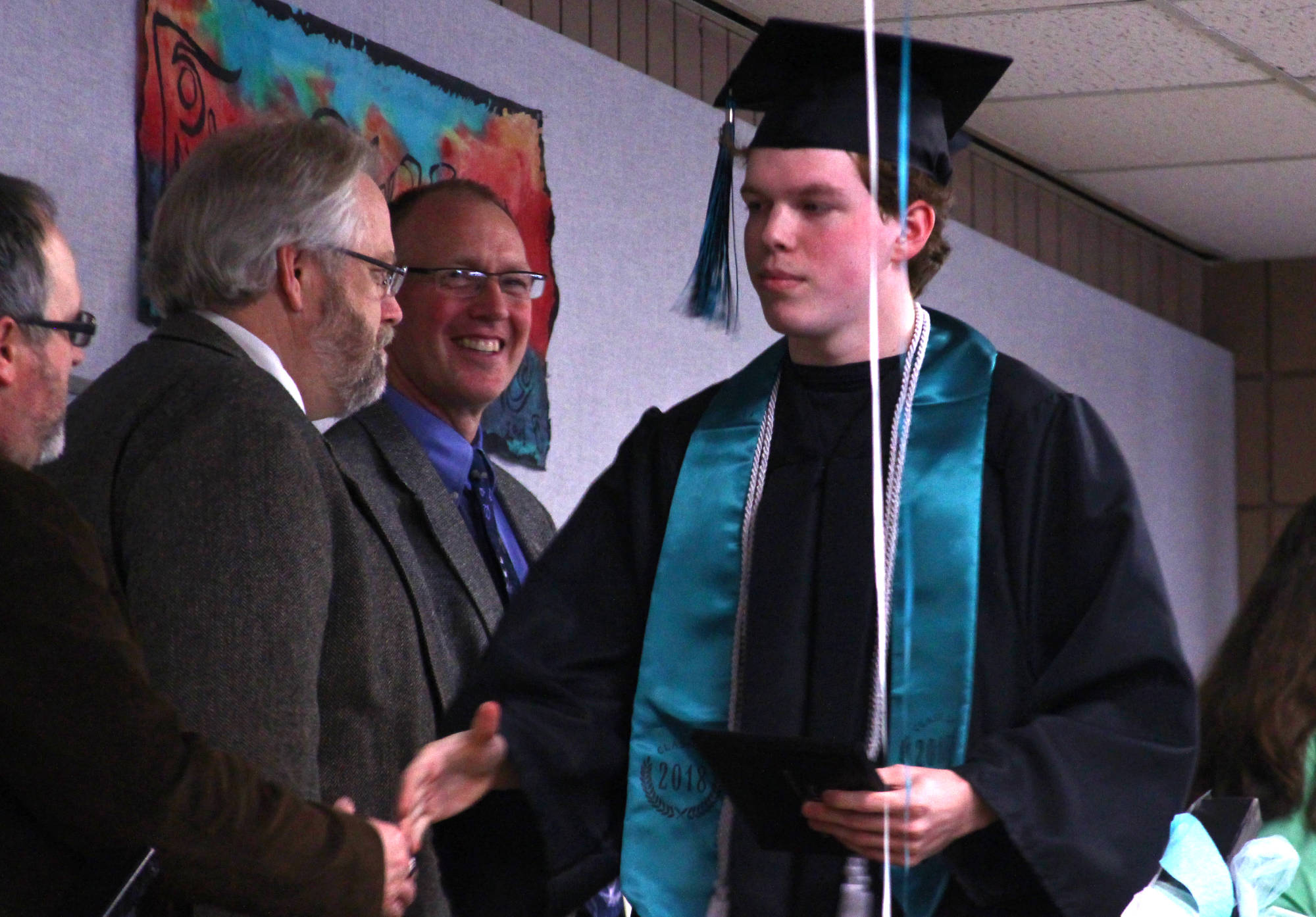 After accepting his diploma, River City Academy graduate Maxwell Mock shakes hands with Kenai Peninsula School Board member Marty Anderson during River City’s graduation ceremony at the Soldotna Regional Sports Complex on Monday, May 21, 2018 in Soldotna, Alaska. (Ben Boettger/Peninsula Clarion).